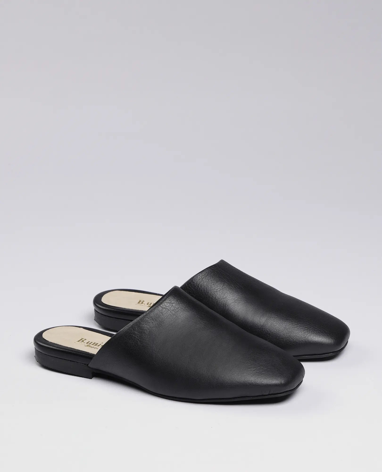 כפכפים שטוחים של B.unique - רוקס בצבע שחור, נעליים נוחות ומסוגננות, מוצגות על רקע לבן.