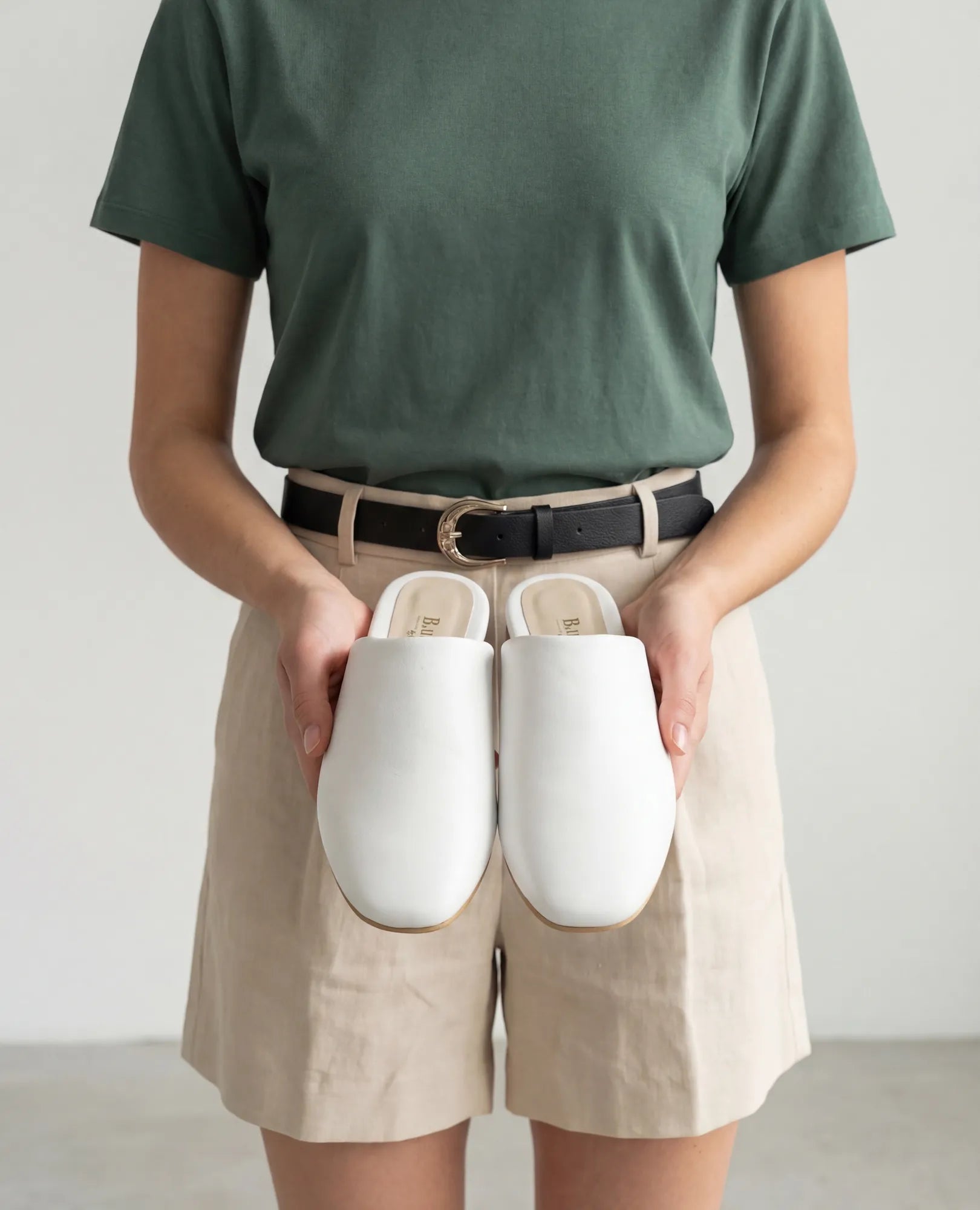 אדם לבוש בחולצה ירוקה ומכנסיים קצרים בצבע בז', נועל כפכפים שטוחים מדגם "רוקס" של המותג B.unique, ומציג מראה ייחודי.