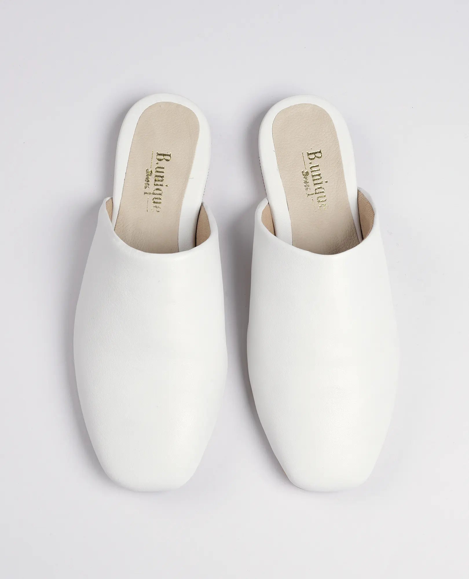 זוג כפכפים שטוחים בצבע לבן – דגם "רוקס" מבית B.unique עם קצה מרובע, מוצגים על רקע לבן חלק.