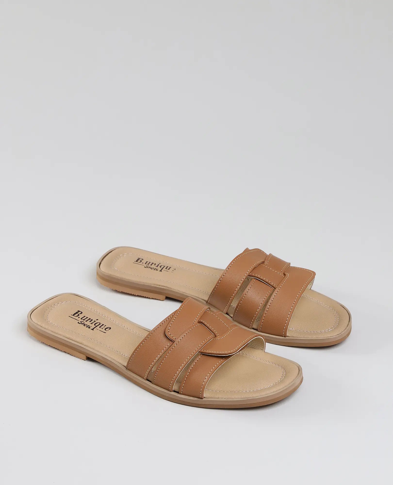 זוג כפכפי רצועות מדגם "קאמל" של המותג B.unique, עם פרטים תפורים, על רקע לבן חלק.