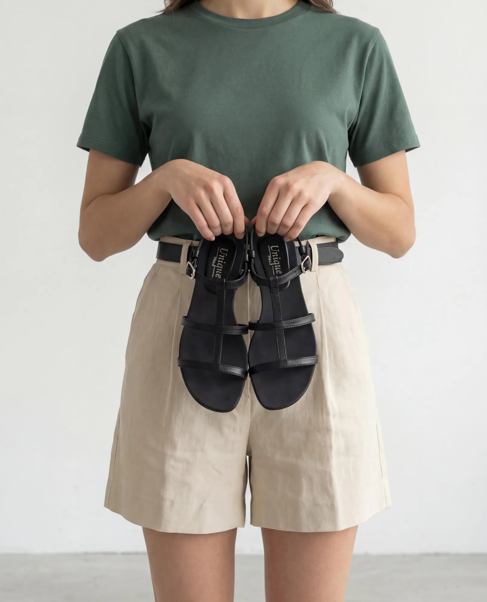 אישה בחולצת טריקו ירוקה ובמכנסיים קצרים בצבע בז', נועלת סנדלי גלדיאטור-קיילי מבית B.unique.