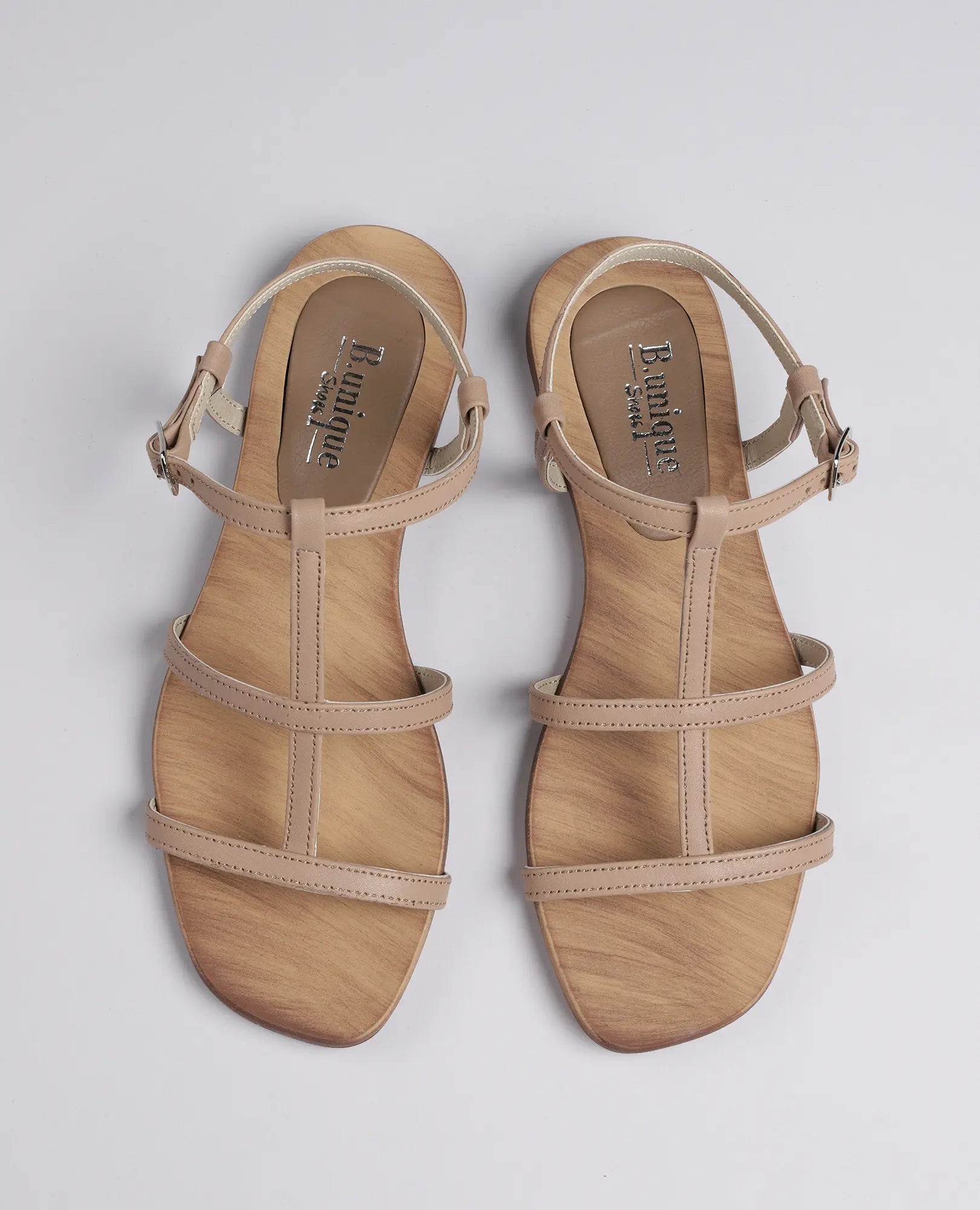 סנדלי גלדיאטור-קיילי מבית B.unique בצבע בז', עם רצועות קרסול וסוליה דמוית עץ.