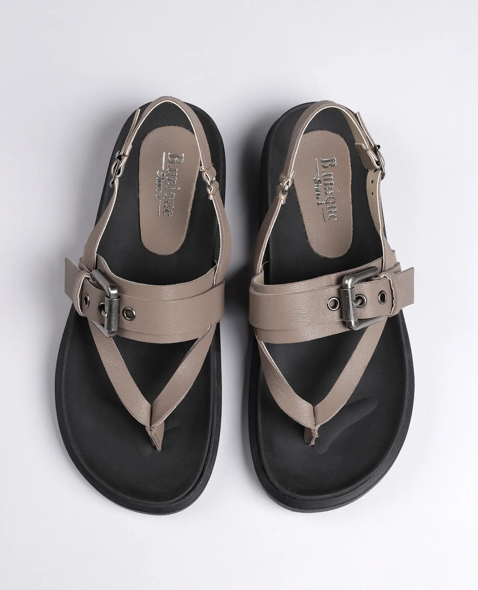 זוג סנדלי אצבע של B.unique מדגם "פואט" בצבע טאופ, עם רצועת אבזם וסוליות שחורות על רקע בהיר אחיד.