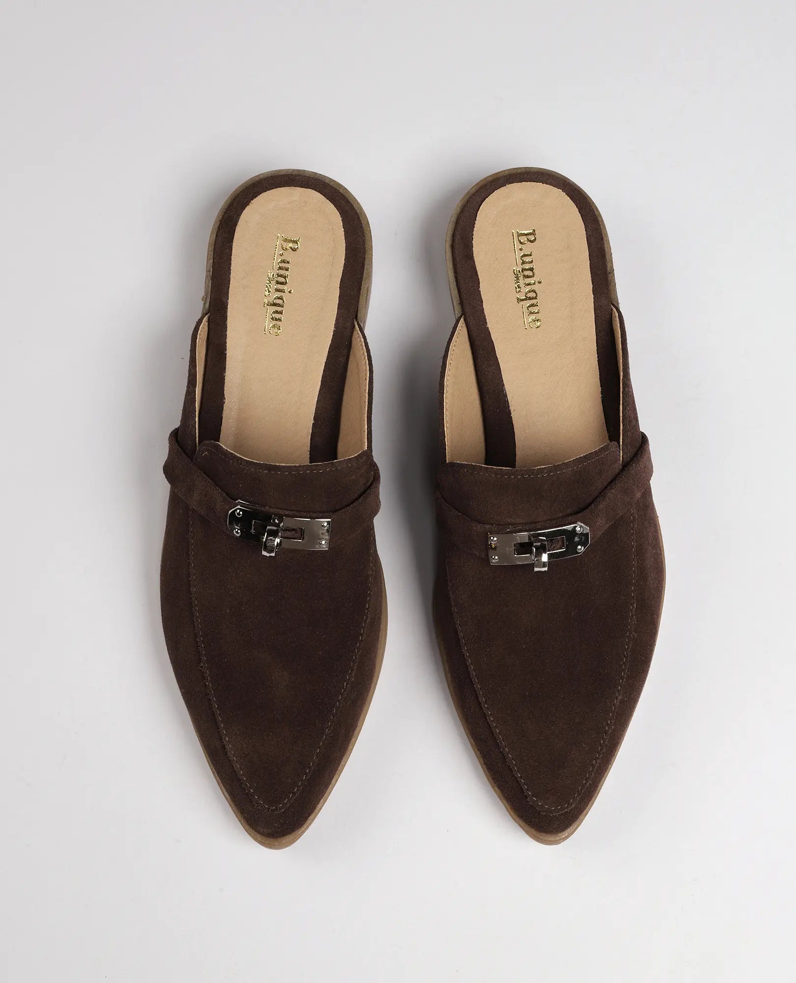 זוג כפכפי מוקסין- ניקי brown suede loafers עם קצות מחודדים ואבזם מתכתי על רקע לבן.