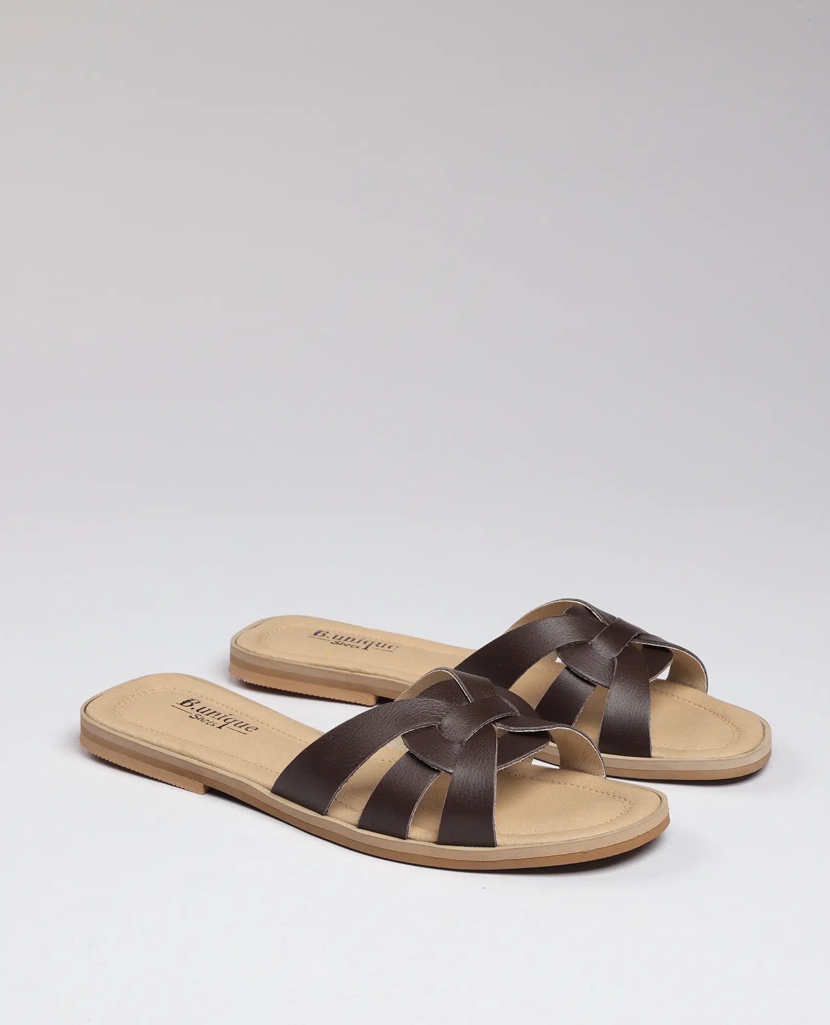 זוג כפכפי רצועות של B.unique - ריבר, כפכפים בצבע חום בהיר עם רצועות חומות מצטלבות על רקע בהיר אחיד.