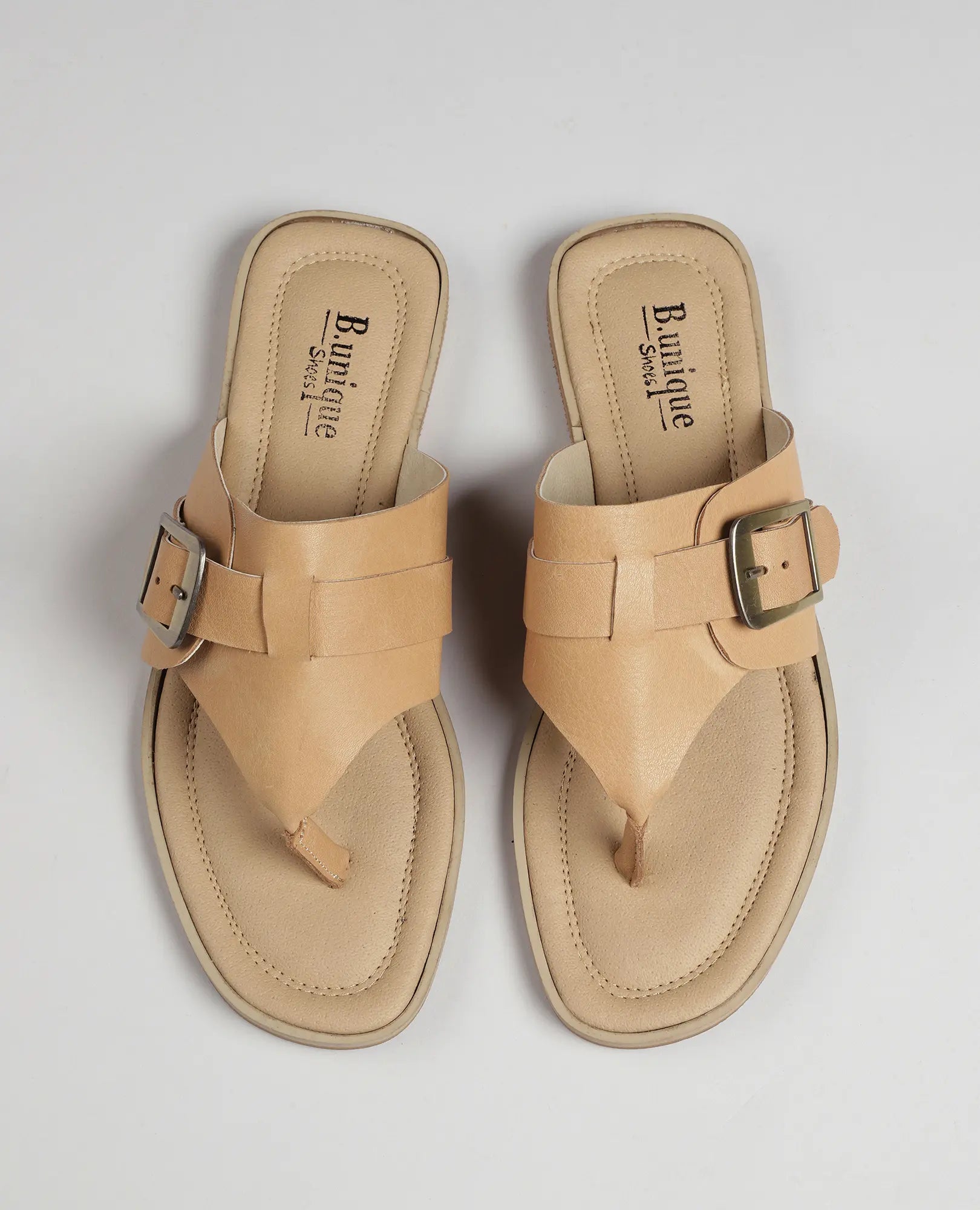 זוג כפכפי אצבע של B.unique עם אבזם – כפכפי אצבע בצבע חום בהיר עם רצועות רחבות ואבזמי מתכת גדולים.