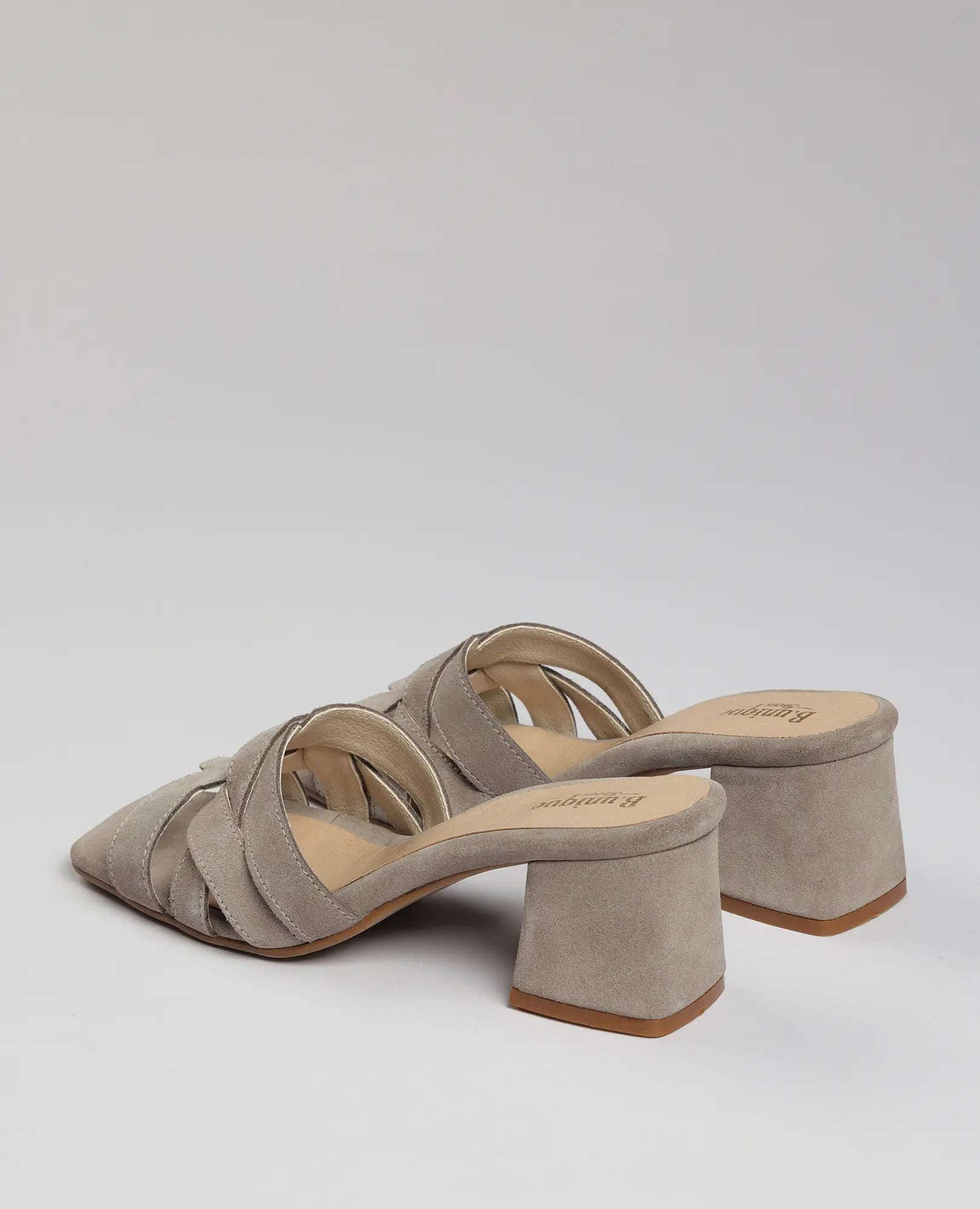 כפכפי עקב מרגי מבית B.unique מעור זמש בצבע טאופ, עם רצועות מצטלבות ועקב רחב, מוצגים על רקע בהיר.