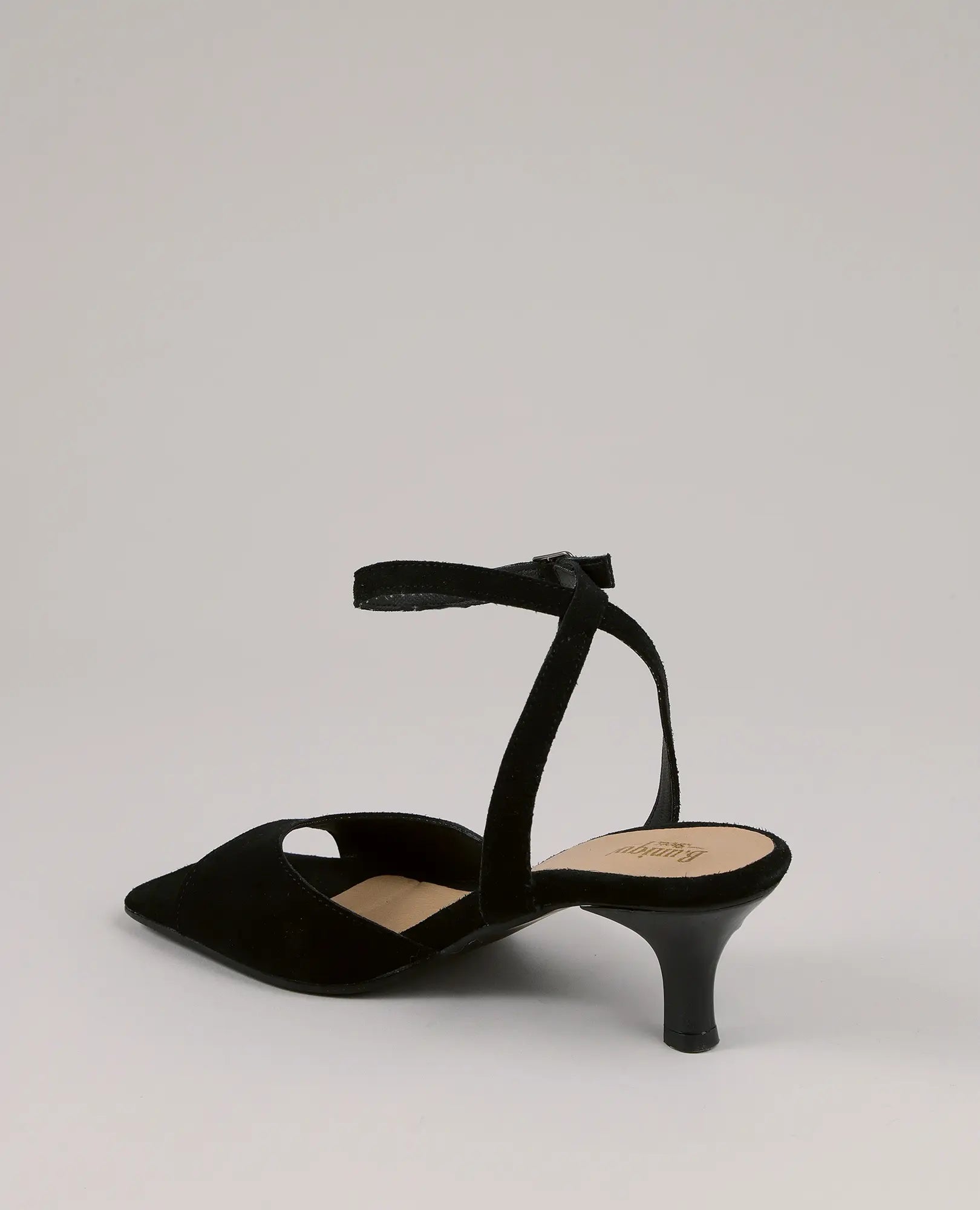 נעלי עקב - דגם "נייה" של B.unique מעור זמש שחור עם רצועת קרסול, קצה מחודד וצד פתוח על רקע חלק.