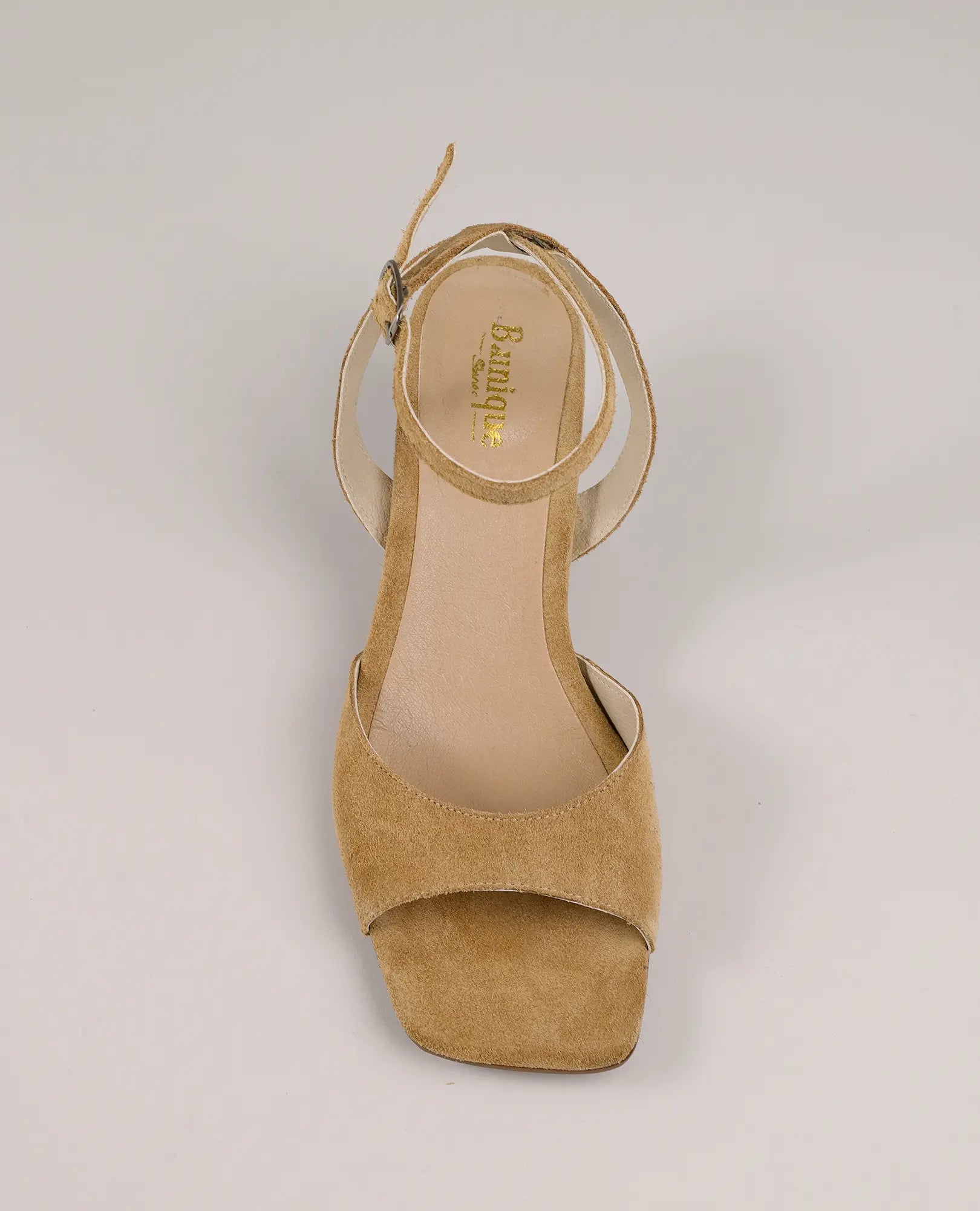סנדלי עקב מעור זמש בגוון טאן עם רצועת קרסול ועקב נמוך מבית B.unique, מוצגים על רקע בהיר.