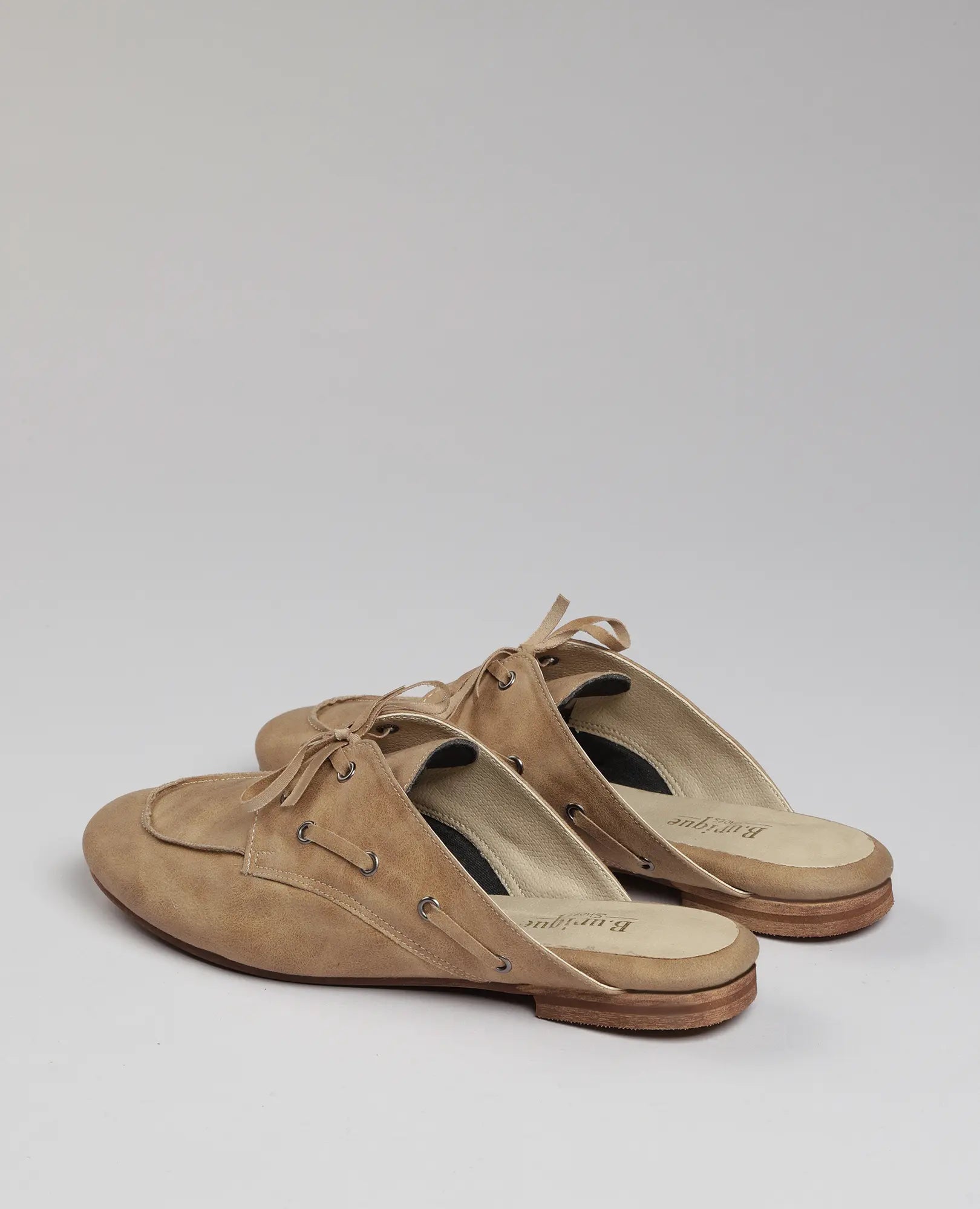 כפכפי מוקסין-לירי דמוי עור בצבע טאן של B-Unique VEGAN עם שרוכים ועקבי עץ, על רקע אפור בהיר.