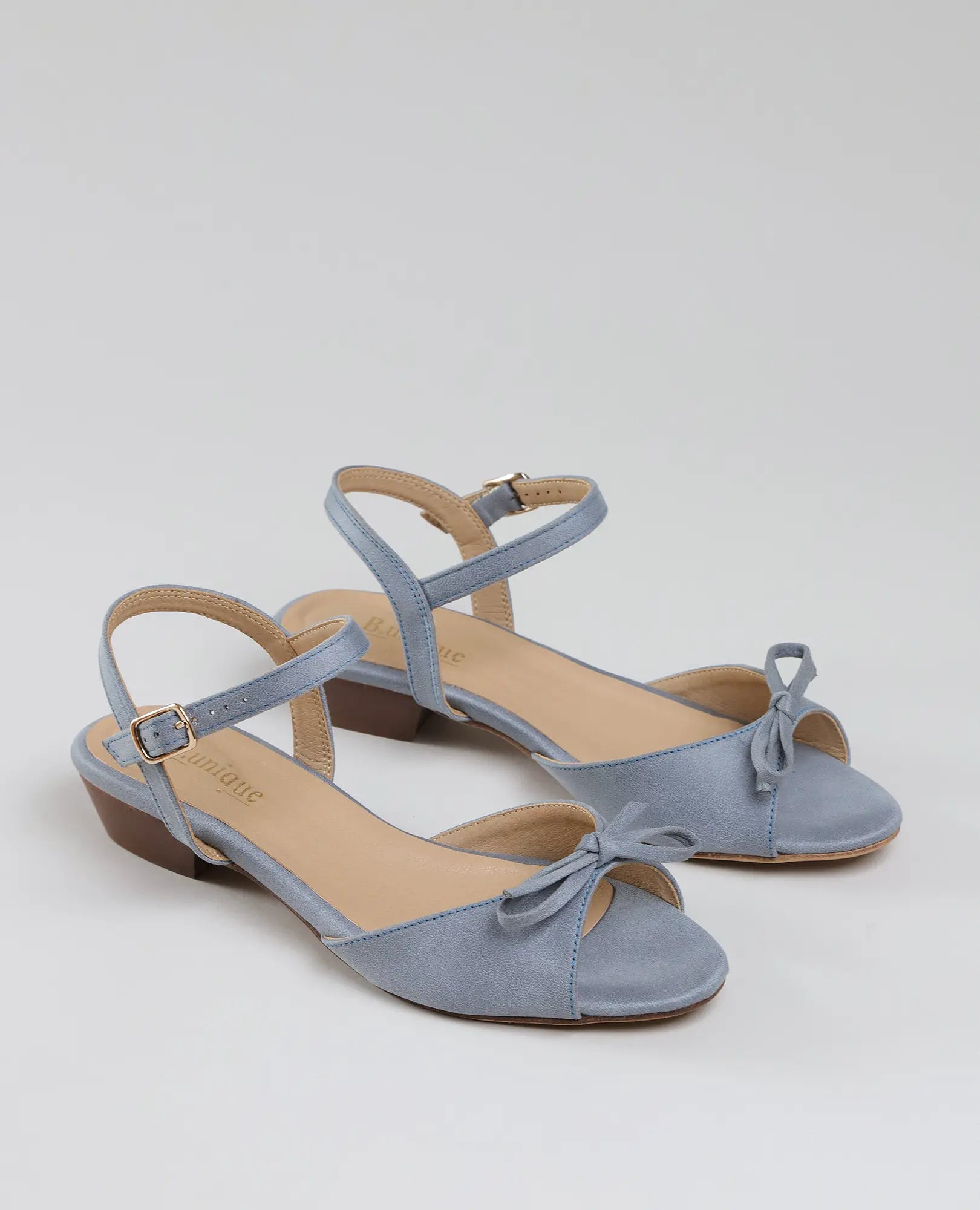 B-Unique VEGAN – סנדלי פפיון קשורים – דגם "קלאודיה" בצבע תכלת, עם עקב נמוך, רצועות קרסול וקישוט פפיון בחזית.