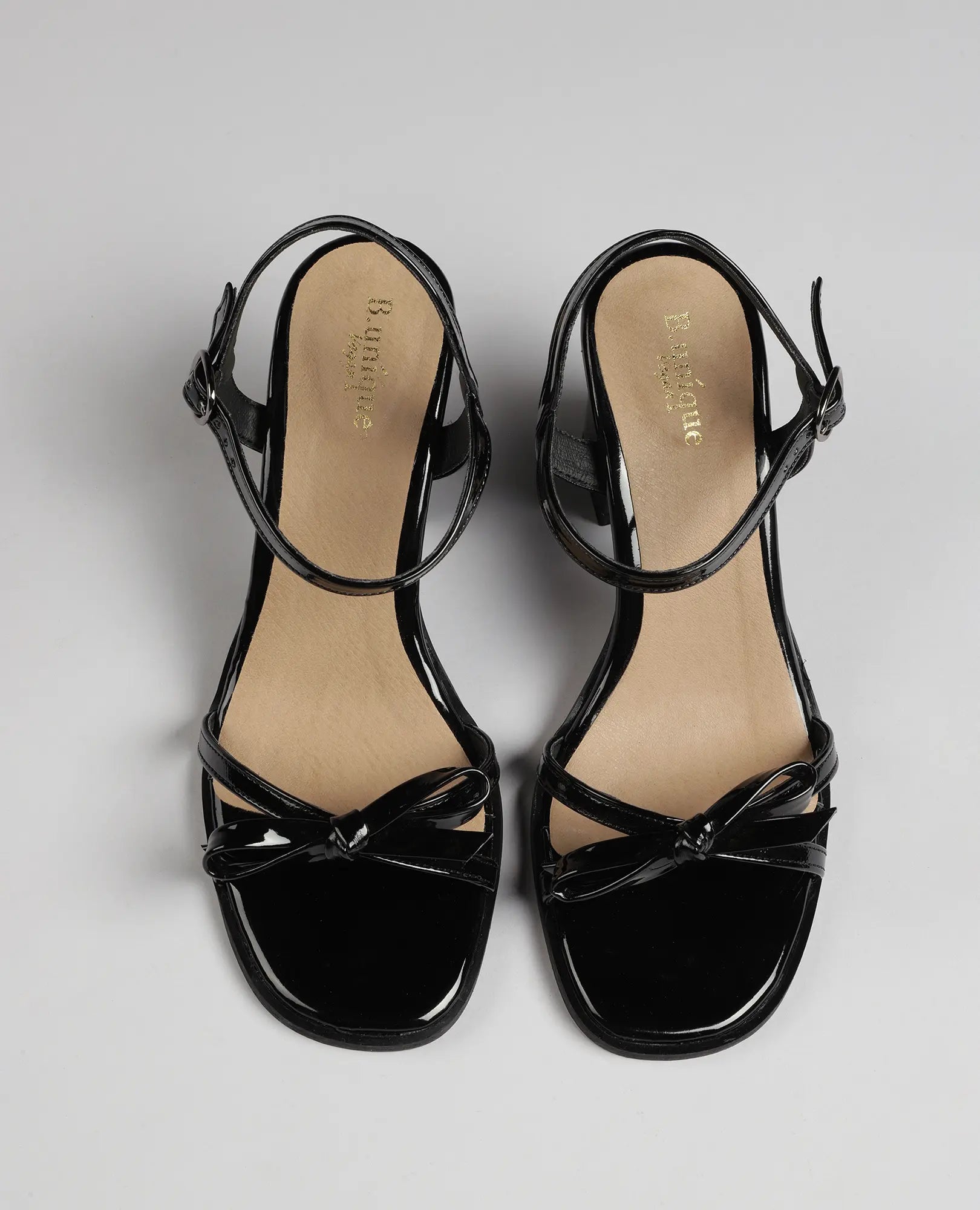 סנדלי עקב עם רצועת פפיון של B-Unique VEGAN, מעור דמוי עור בצבע שחור מבריק עם פפיון ורצועות קרסול.