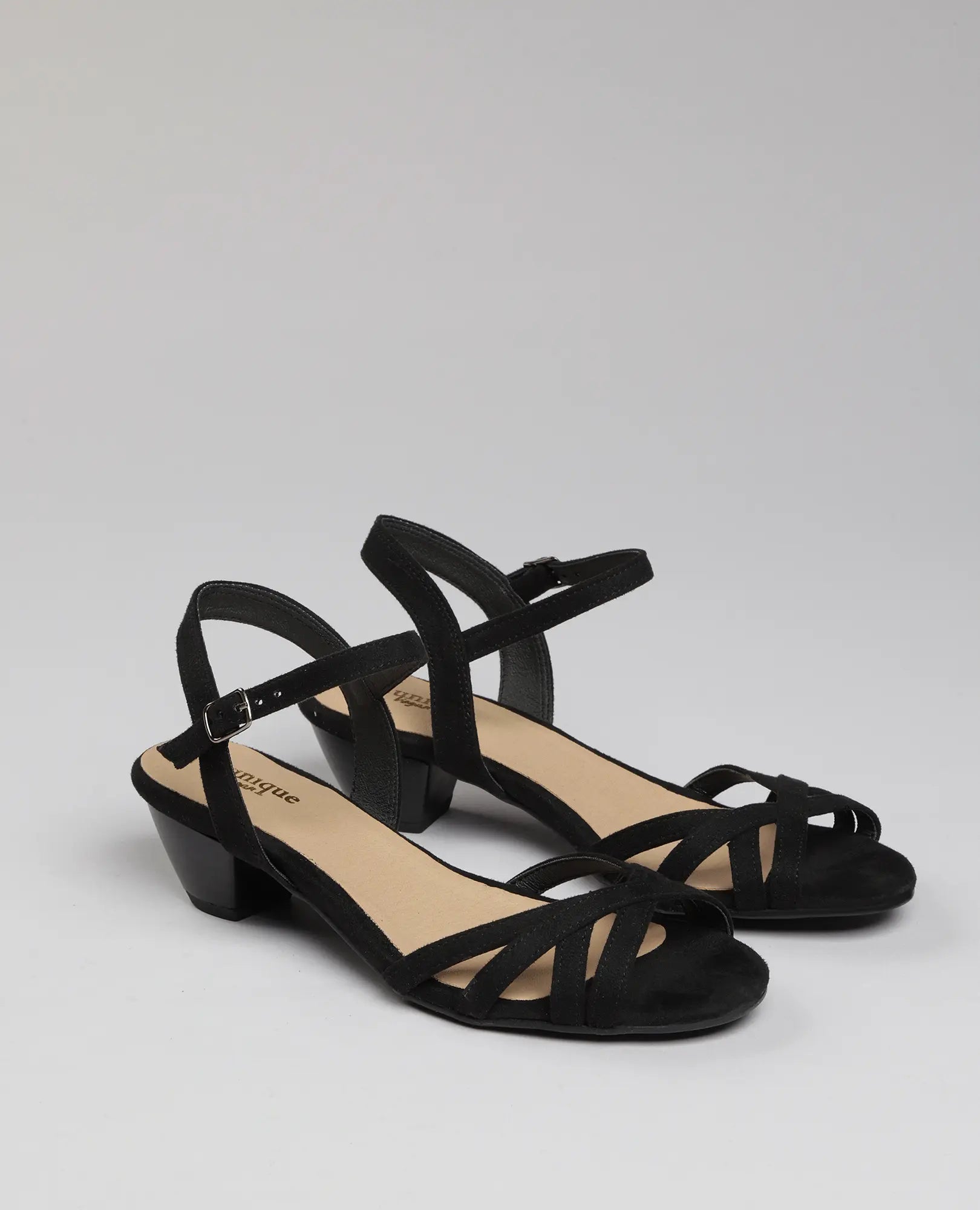 סנדלי עקב שחורים של B-Unique VEGAN עם רצועות דקות ועיצוב קרוס-אובר על רקע חלק.