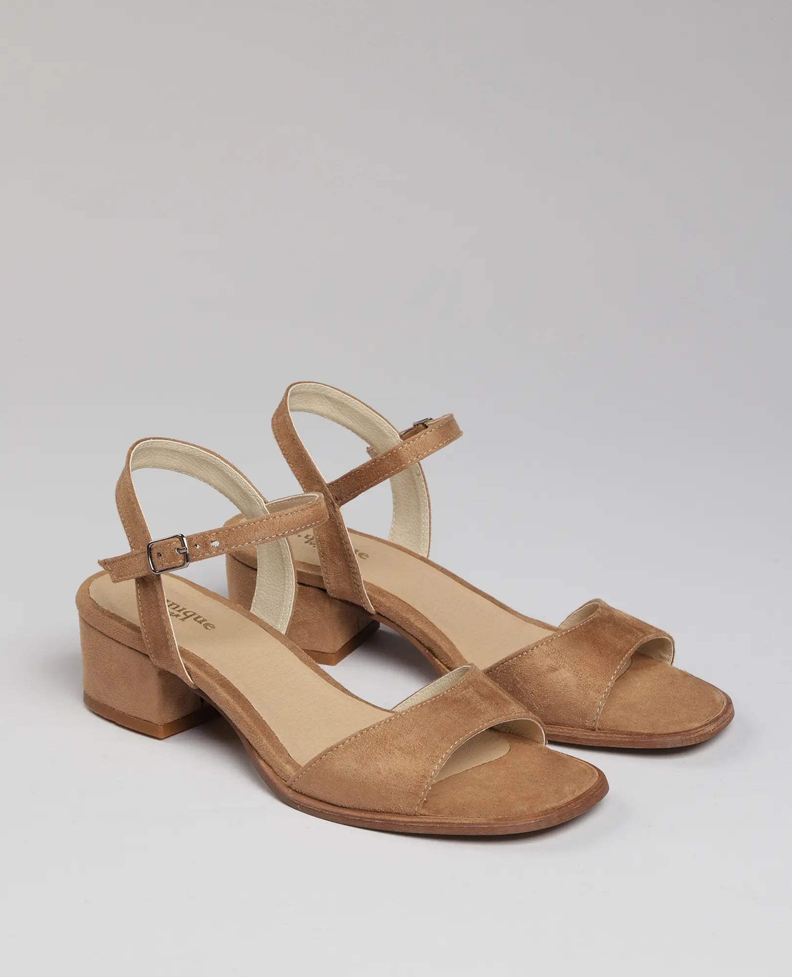 זוג סנדלי עקב-לאב של B-Unique VEGAN בצבע קאמל, עם רצועות בקרסול ועקב בינוני, מוצגים על רקע אחיד.
