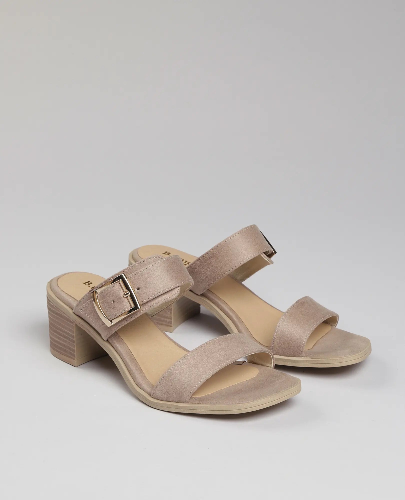 כפכפי עקב "פרנקי" של B-Unique VEGAN בגוון בז', עם שתי רצועות ואבזם זהב גדול, על רקע בהיר.