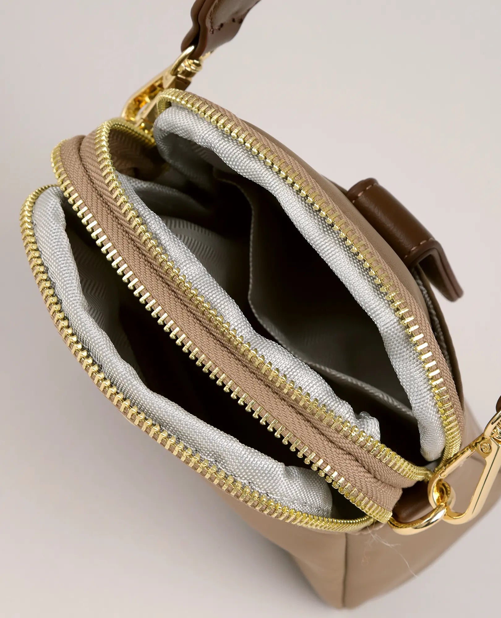 מבט מלמעלה על תיק צד לנייד "לונה" מבית B-Unique Bags בצבע חום, עם רוכסנים זהובים, בטנה אפורה ושני תאים פתוחים.