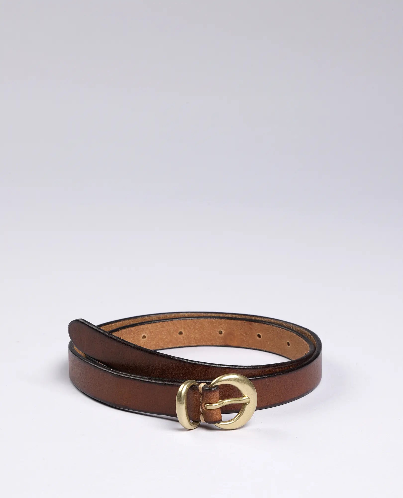 חגורת עור צרה עם אבזם זהב מדגם "דני" של B Unique מונחת מגולגלת על רקע לבן.