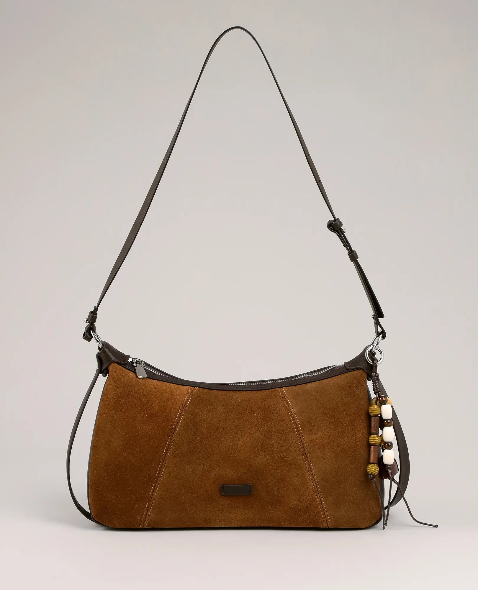 תיק צד מעור זמש של B-Unique Bags עם רצועה דקה מתכווננת וחרוזים תלויים, על רקע חלק.
