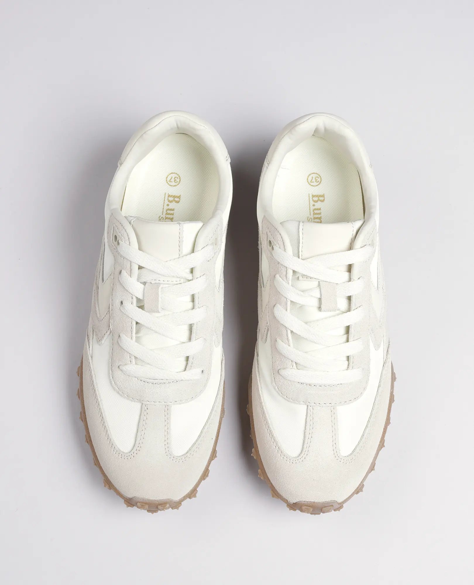 זוג סניקרס מעור זמש- נטשה מבית B.unique בצבע לבן ובז' עם סוליות גומי, נראות מלמעלה על רקע בהיר אחיד.