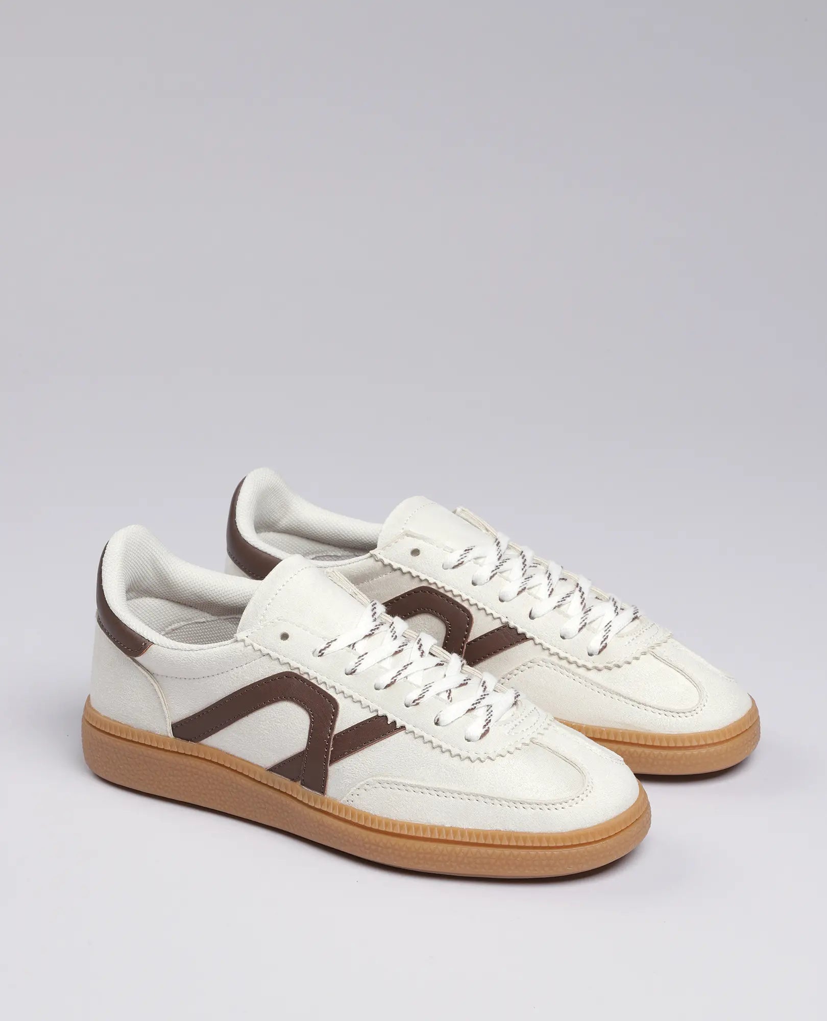 סניקרס דמוי זמש- נווה מבית B-Unique VEGAN בלבן עם הדגשות חומות וסוליות גומי חומות, על רקע אפור בהיר.