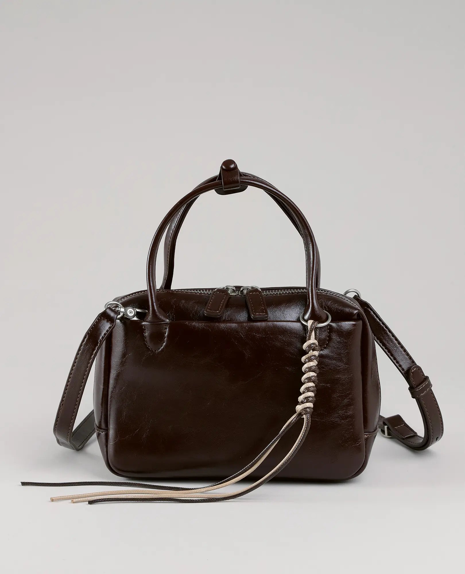 תיק צד מיני מזוודה-וינה מבית B-Unique Bags בצבע חום, עם שתי ידיות, רצועת כתף וציציות מעוצבות.