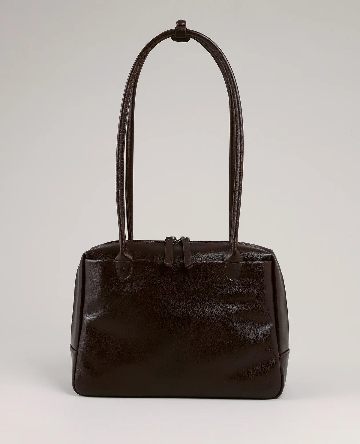 תיק צד קדמי בצבע חום כהה מבית B-Unique Bags, עם שתי ידיות ארוכות וסגירת רוכסן, מושלם לשילוב עם נעלי נשים.