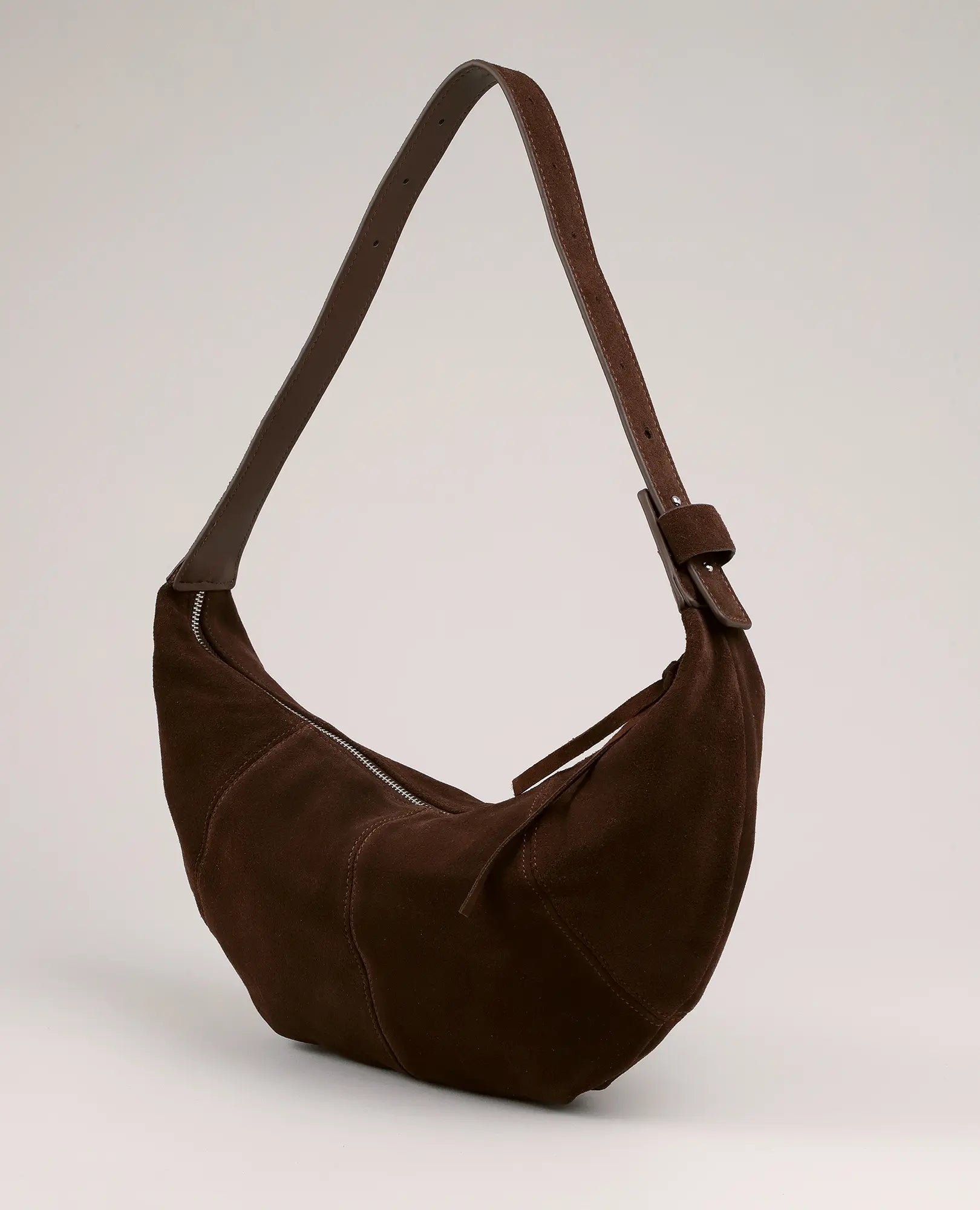תיק "פאוץ ירח - עינב" מבית B-Unique Bags: תיק כתף מעור זמש חום עם רצועה רחבה ורוכסן כסוף על רקע בהיר.