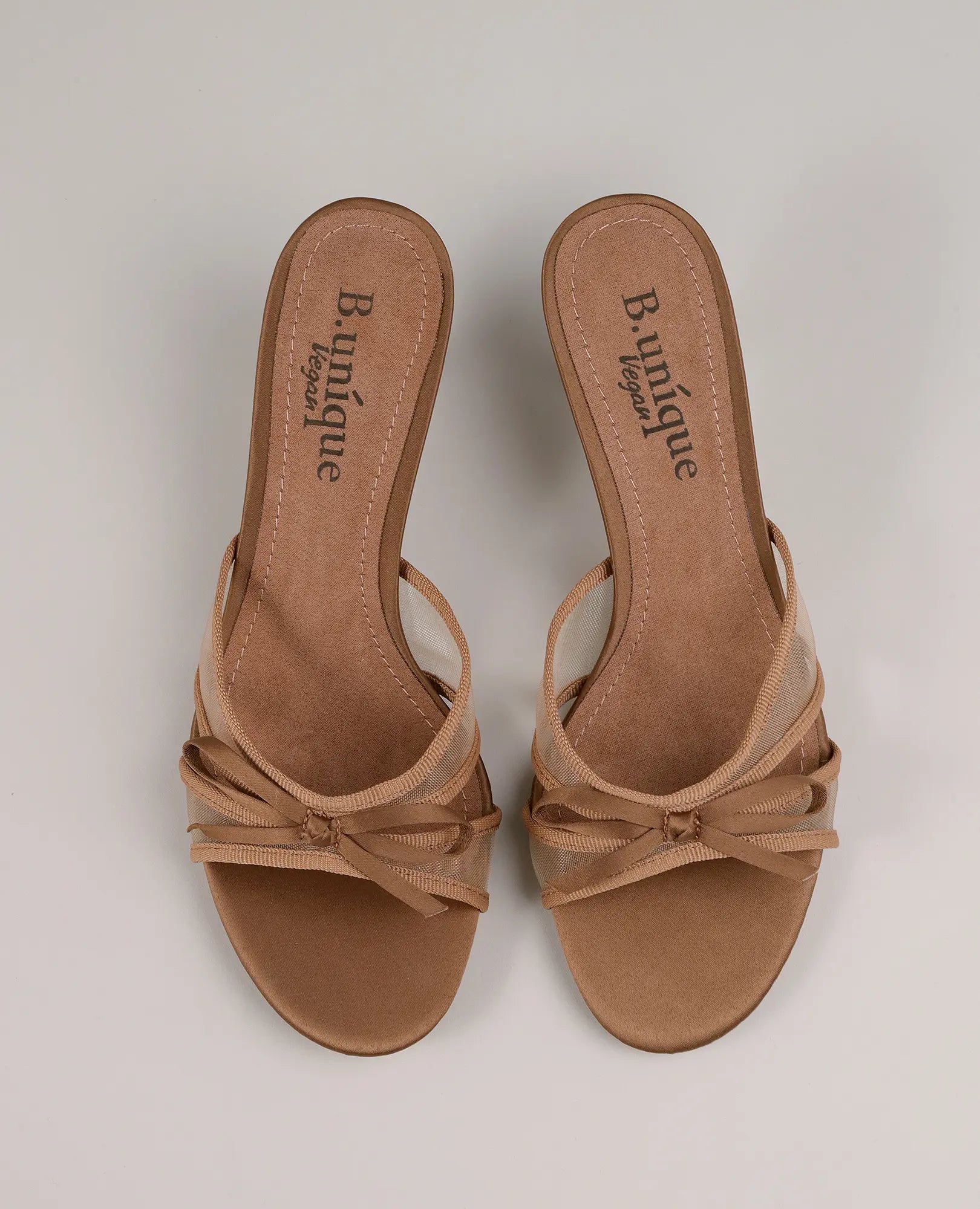 זוג כפכפי עקב "פאר" מבית B-Unique VEGAN עם רצועות דקות, רצועות מצטלבות ופרט של קשת על רקע ניטרלי.