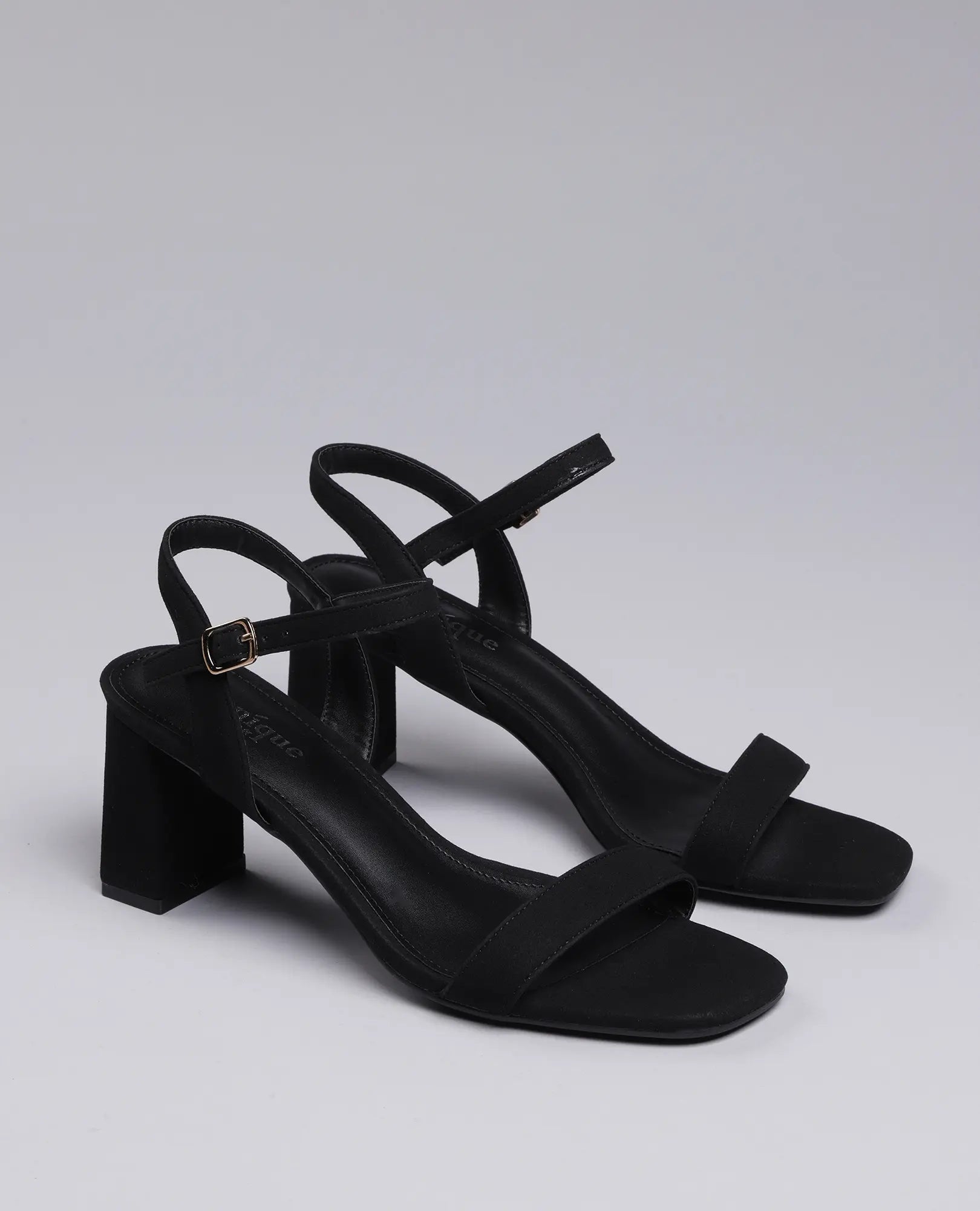 זוג נעלי עקב B-Unique VEGAN סנדלי עקב- אפריל בצבע שחור עם רצועות בקרסול, אצבעות פתוחות ועקבים רחבים בצבע אפור בהיר.