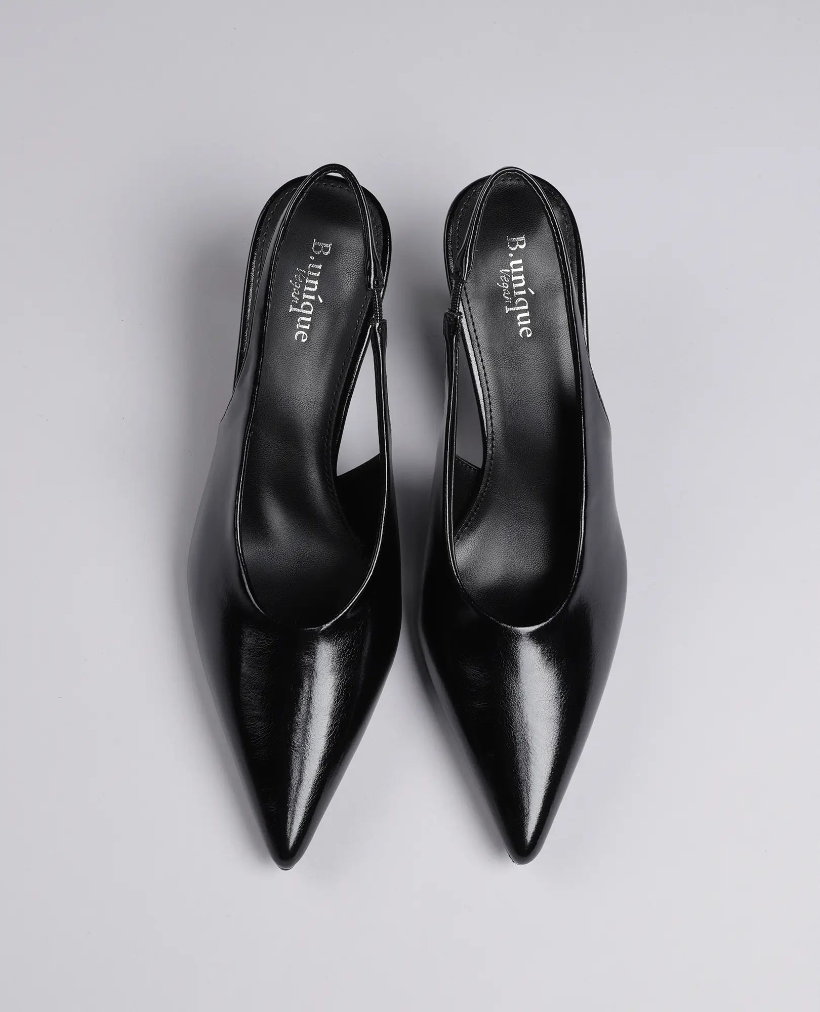 זוג נעלי עקב שפיץ- דורון מבית B-Unique VEGAN, בצבע שחור עם עקב בינוני, על רקע אפור בהיר, מבט מלמעלה.