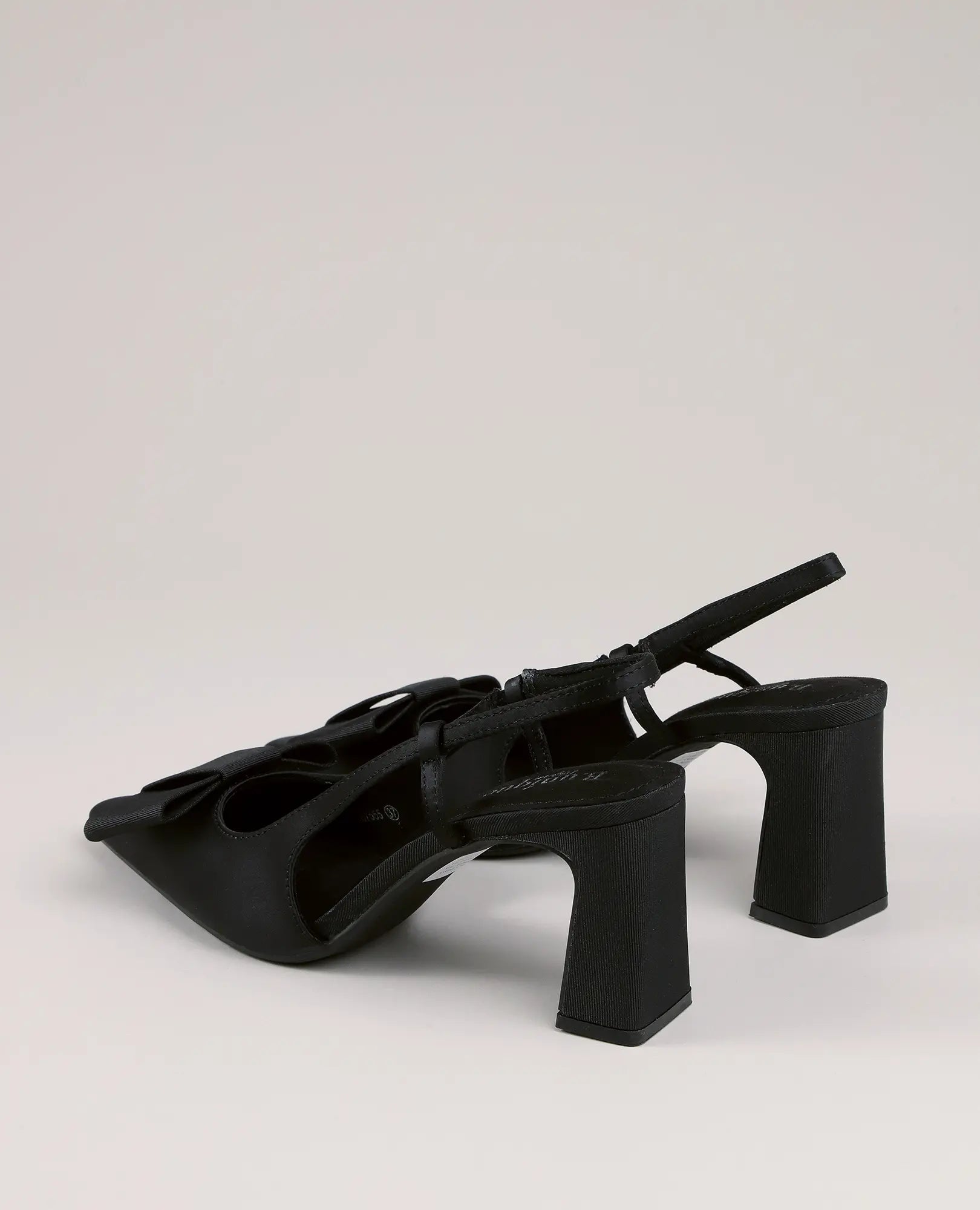 B-Unique VEGAN – סנדלי עקב שחורים עם פפיון, בעיצוב ייחודי, עם חרטום מרובע וקישוטים, מוצגים על רקע בהיר.