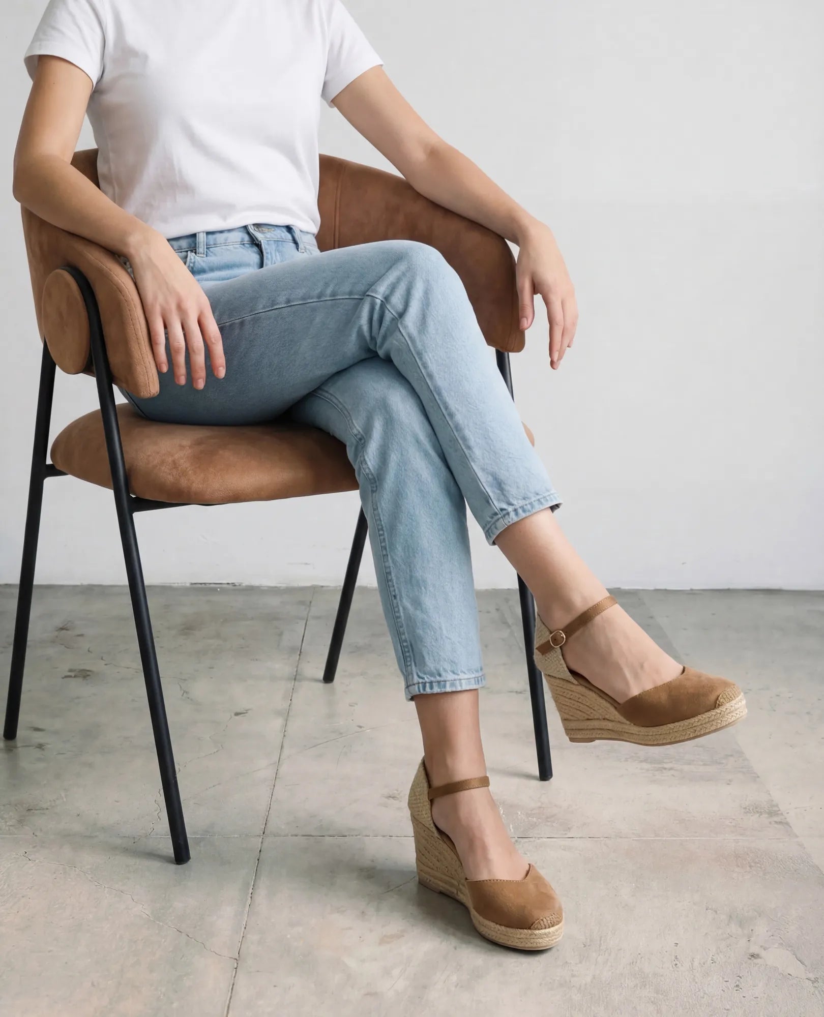 אדם לבוש בחולצת טריקו לבנה ובג'ינס יושב, נועל נעלי פלטפורמה של B-Unique VEGAN - כרם עם רצועת קרסול.