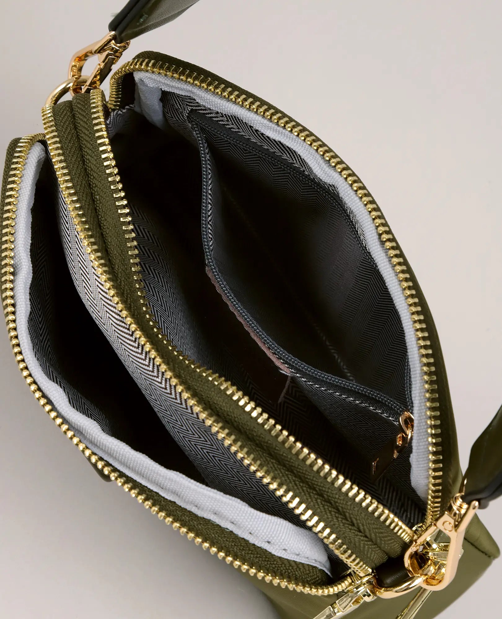 מבט מלמעלה על תיק צד - ויקטוריה מבית B-Unique Bags, בצבע ירוק זית עם רוכסנים מוזהבים, רצועה מתכווננת ותאים מבד בדוגמה.