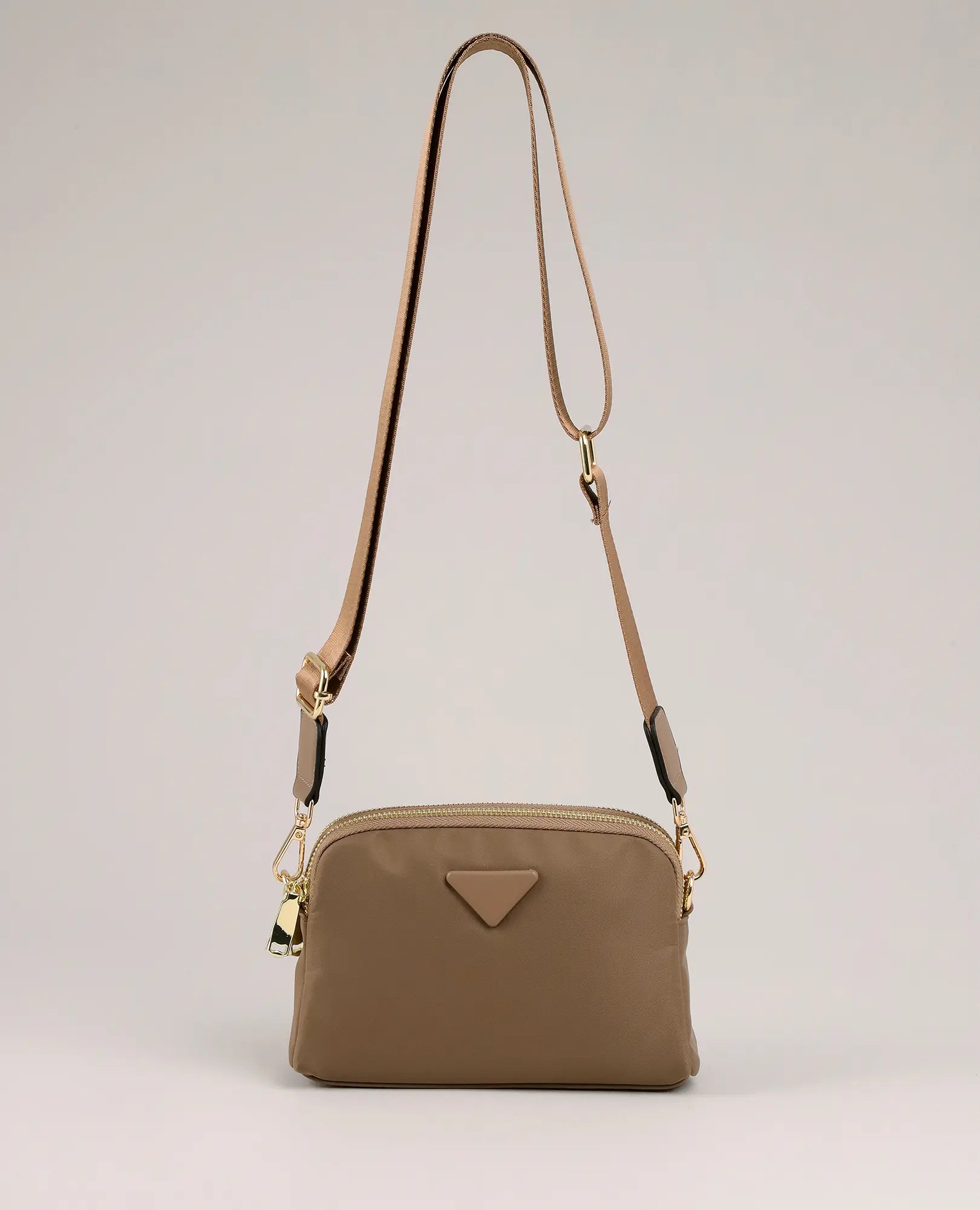 תיק צד "ויקטוריה" מבית B-Unique Bags, ניילון קשיח בצבע בז', רצועה מתכווננת, אבזמי זהב ולוגו משולש קטן.