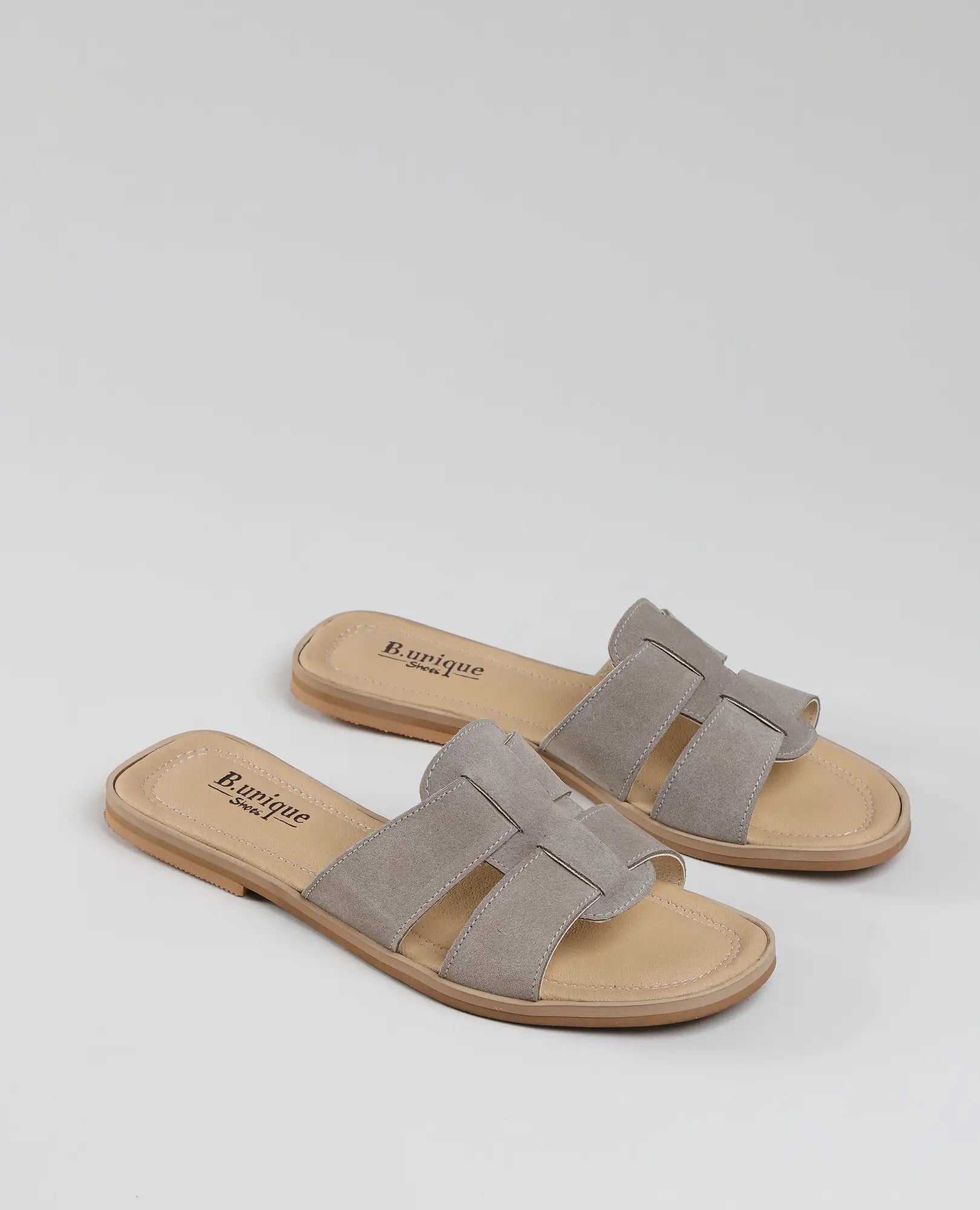 כפכפים שטוחים של B.unique - דגם "מורגן" בצבע טאופ לנשים, עם פתחים באצבעות, מוצגים על רקע לבן.