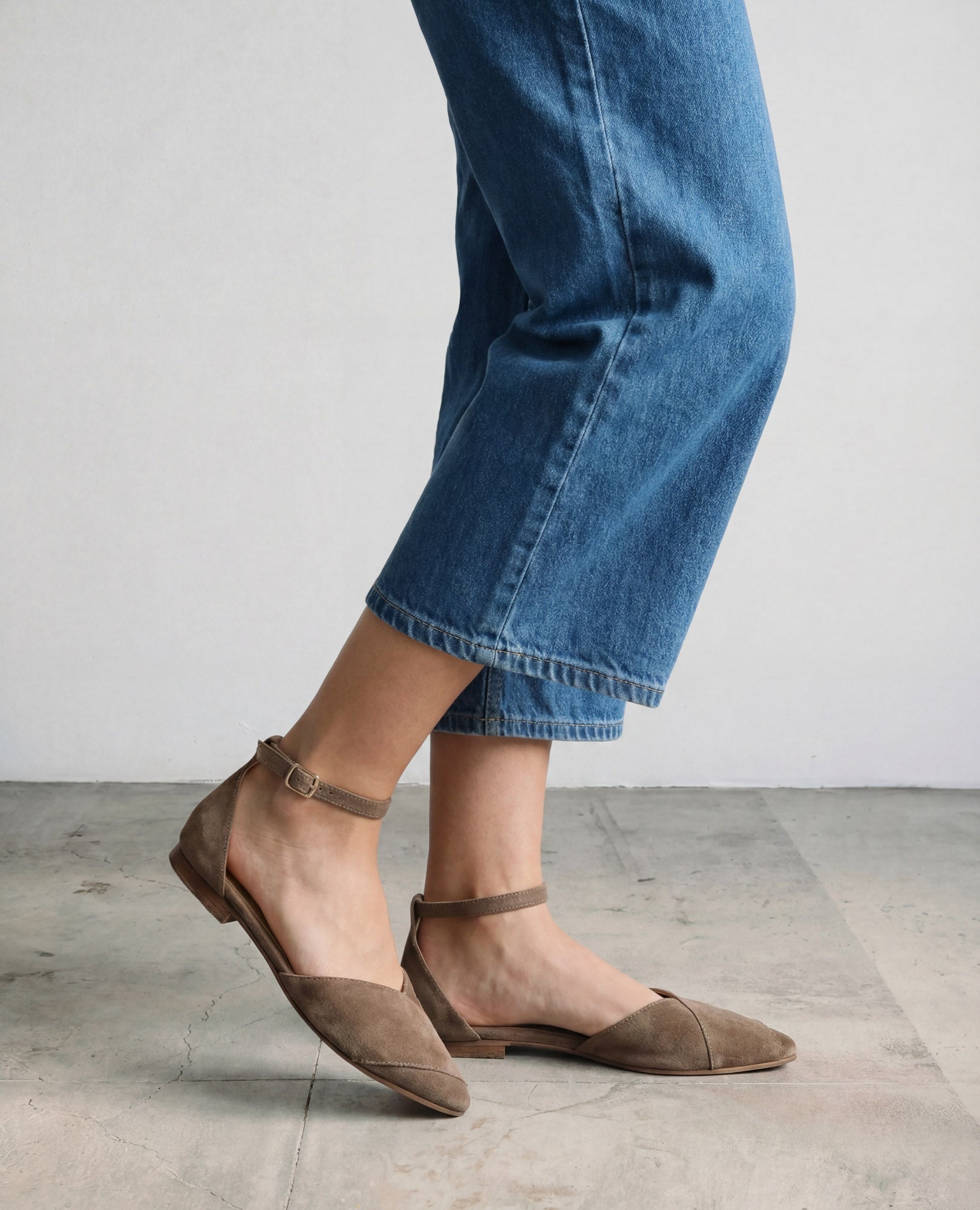 אדם לבוש בג'ינס כחול קצר ונעלי שפיץ של אלני בצבע טאופ מבית B.unique, עומד על רצפה בהירה.