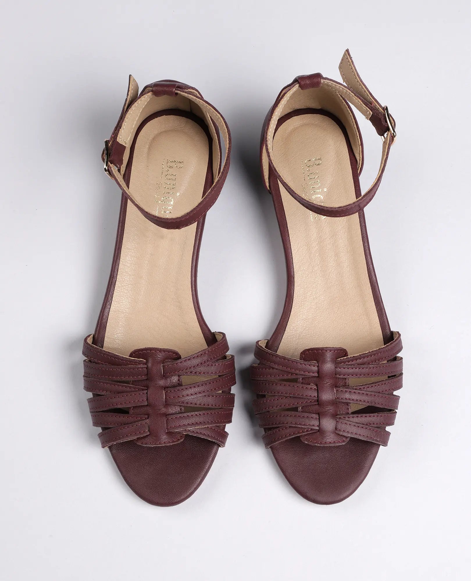 זוג סנדלי רצועות דקות-לוריה מבית B.unique, סנדלים חומים עם אצבעות חשופות, חלק קדמי שזור ורצועות עור, מבט מלמעלה.