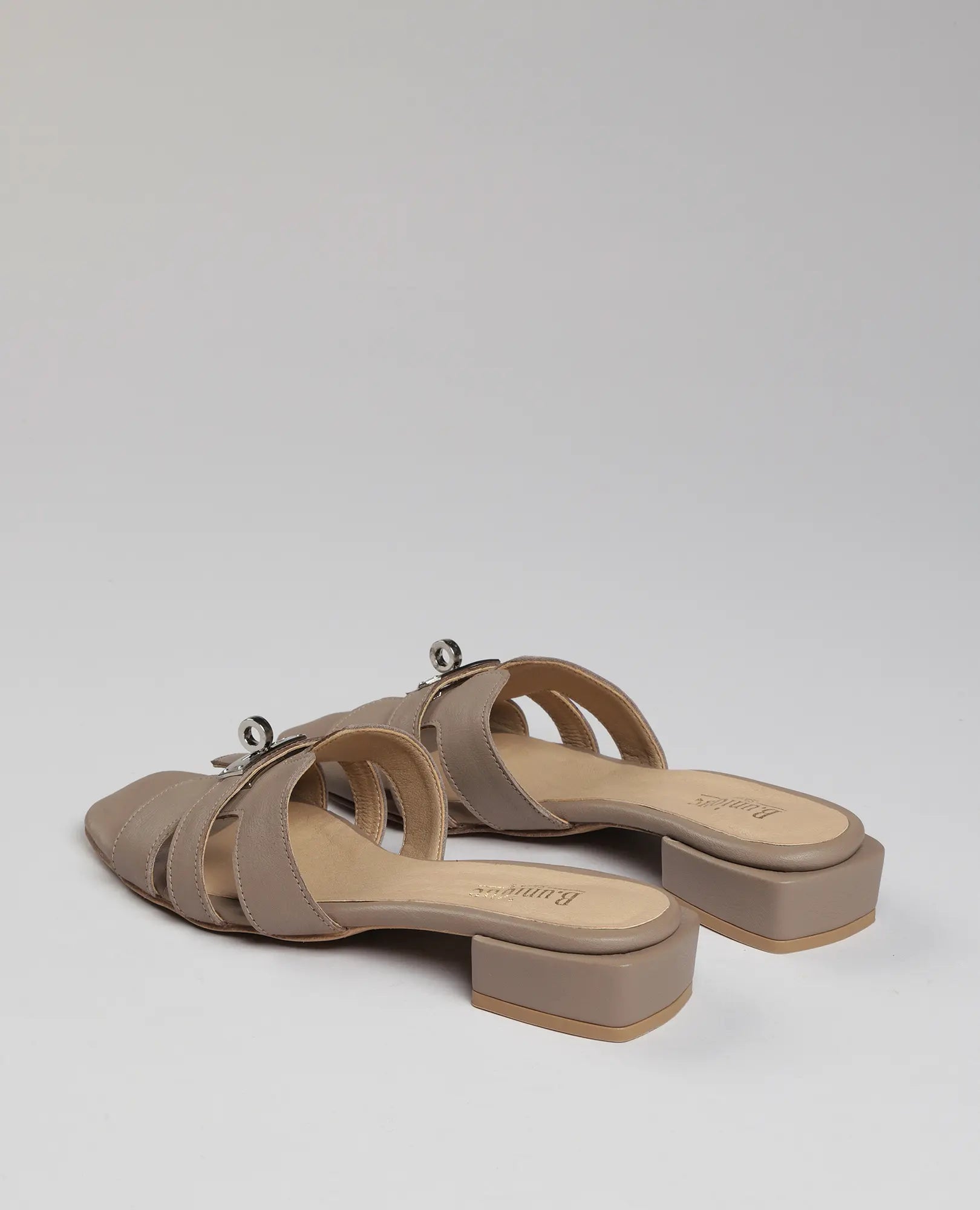 כפכפי רצועות עם אבזם – דגם "נעה" של B.unique, כפכפי עור טאופ עם עקב נמוך, רצועות רחבות ואבזם כסף.