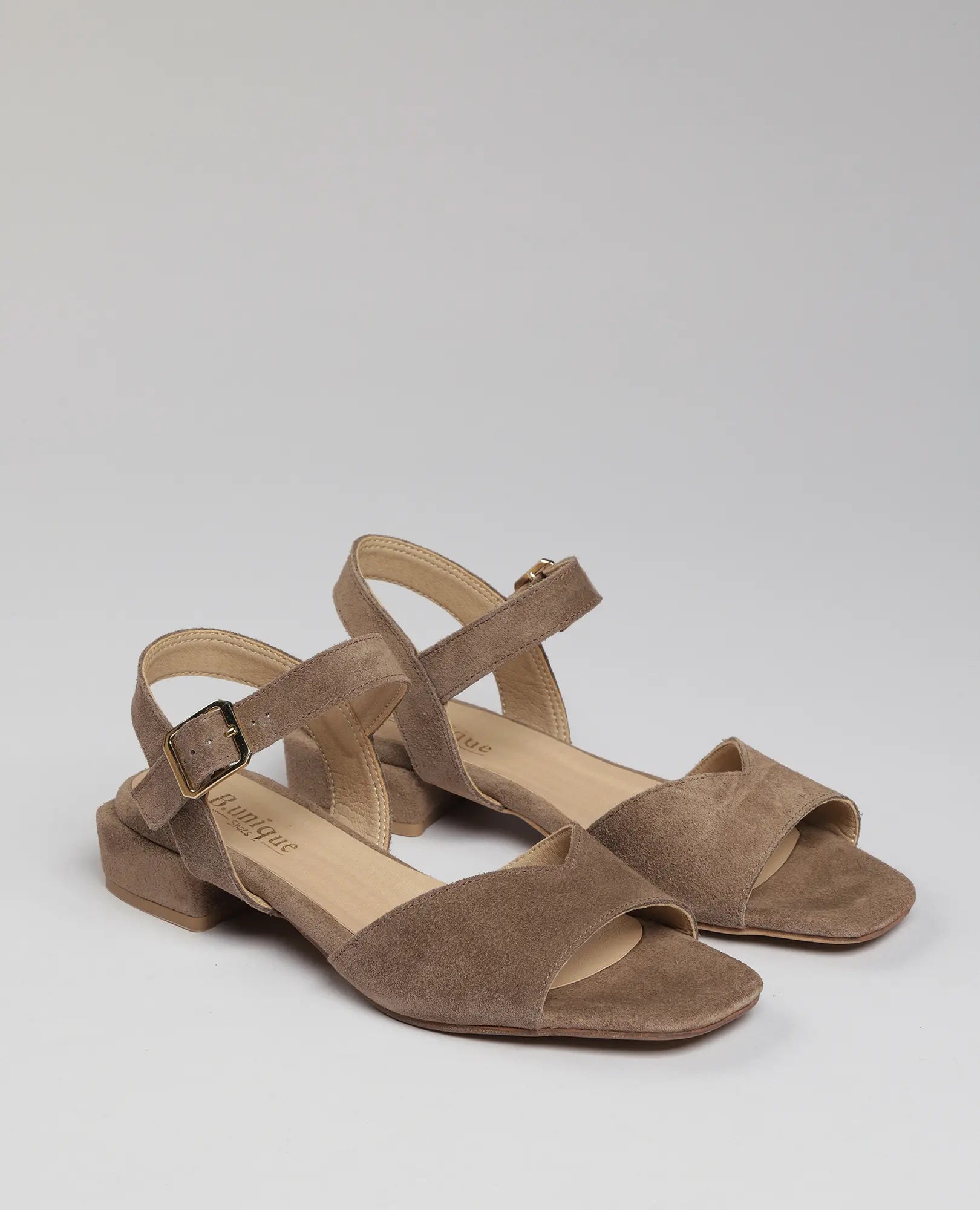 סנדלי B.unique לנשים - דגם "ניר" בצבע טאופ עם רצועות קרסול ועקב נמוך, על רקע בהיר.