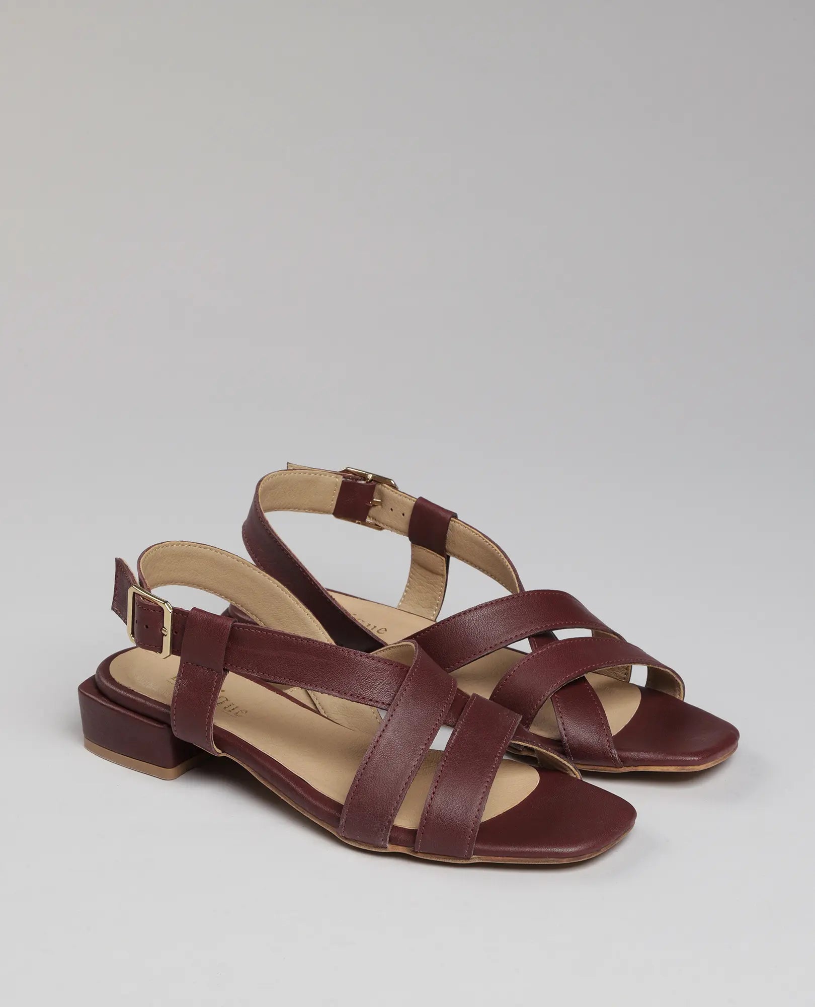 סנדלים שטוחות - דגם "נלה" של B.unique, בצבע בורדו עם רצועות מצטלבות ואבזמים בקרסול, בסגנון אופנתי.