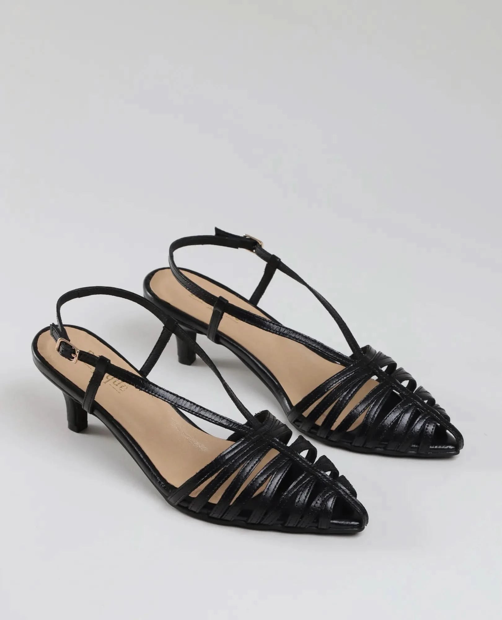 The סנדלי עקב- מיכאלה are black strappy slingback kitten heels with pointed toes, offering a chic look to complete any stylish outfit. Displayed on a light background.