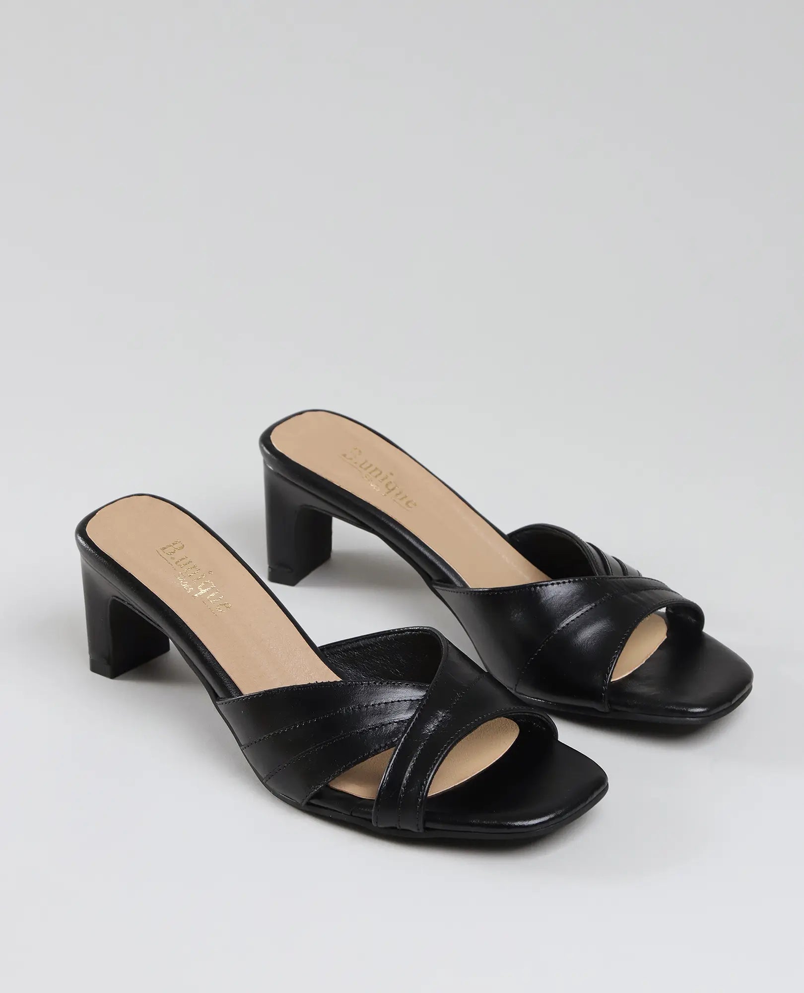 זוג כפכפי עקב של B.unique בצבע ארגמן – נעלי עקב שחורות עם אצבעות חשופות, רצועות מצטלבות ועקב רחב מעור איכותי.