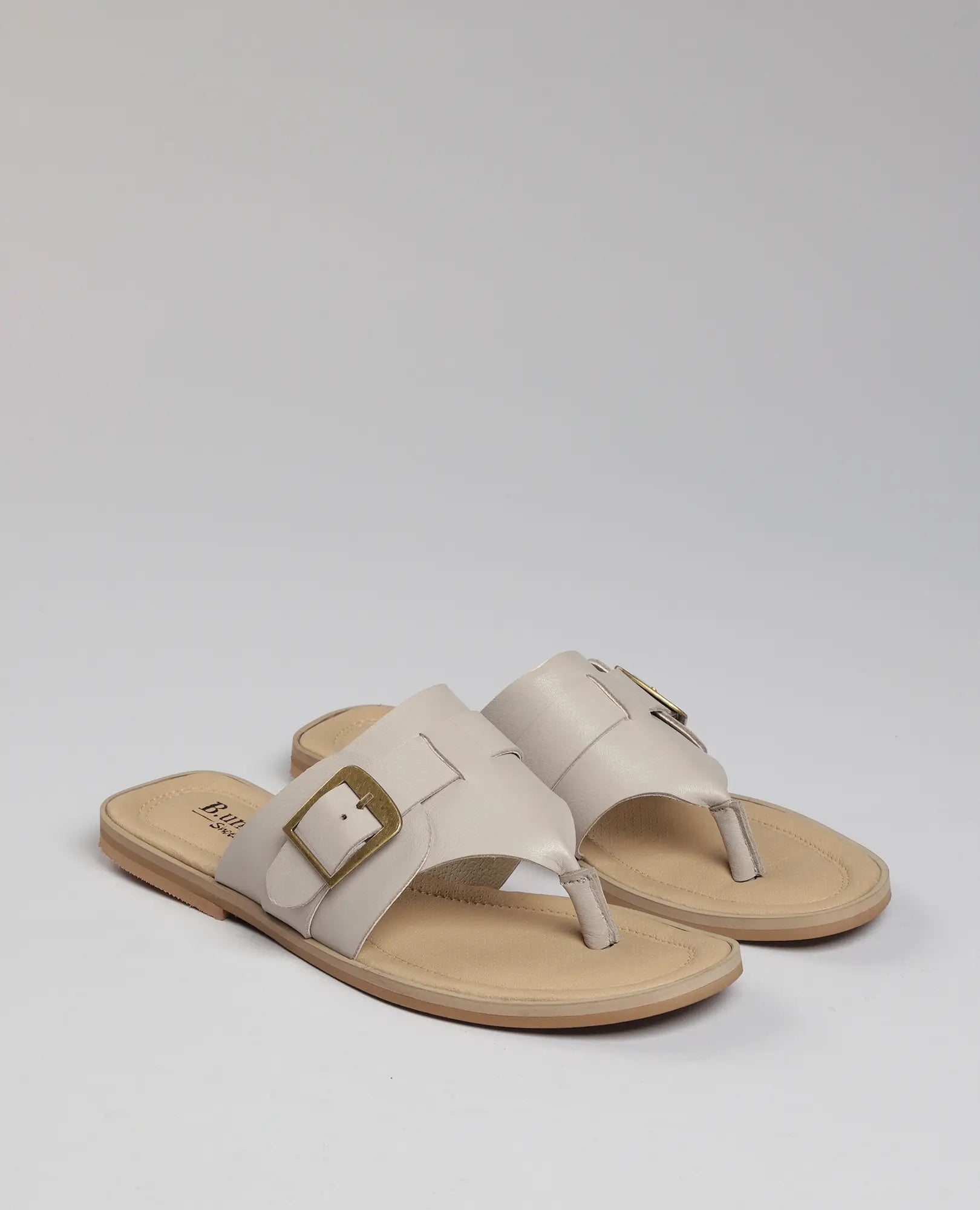 B.unique כפכפי אצבע עם אבזם – לורל בגוון בז', אבזמים מוזהבים וסוליה בצבע טאן, על רקע בהיר.