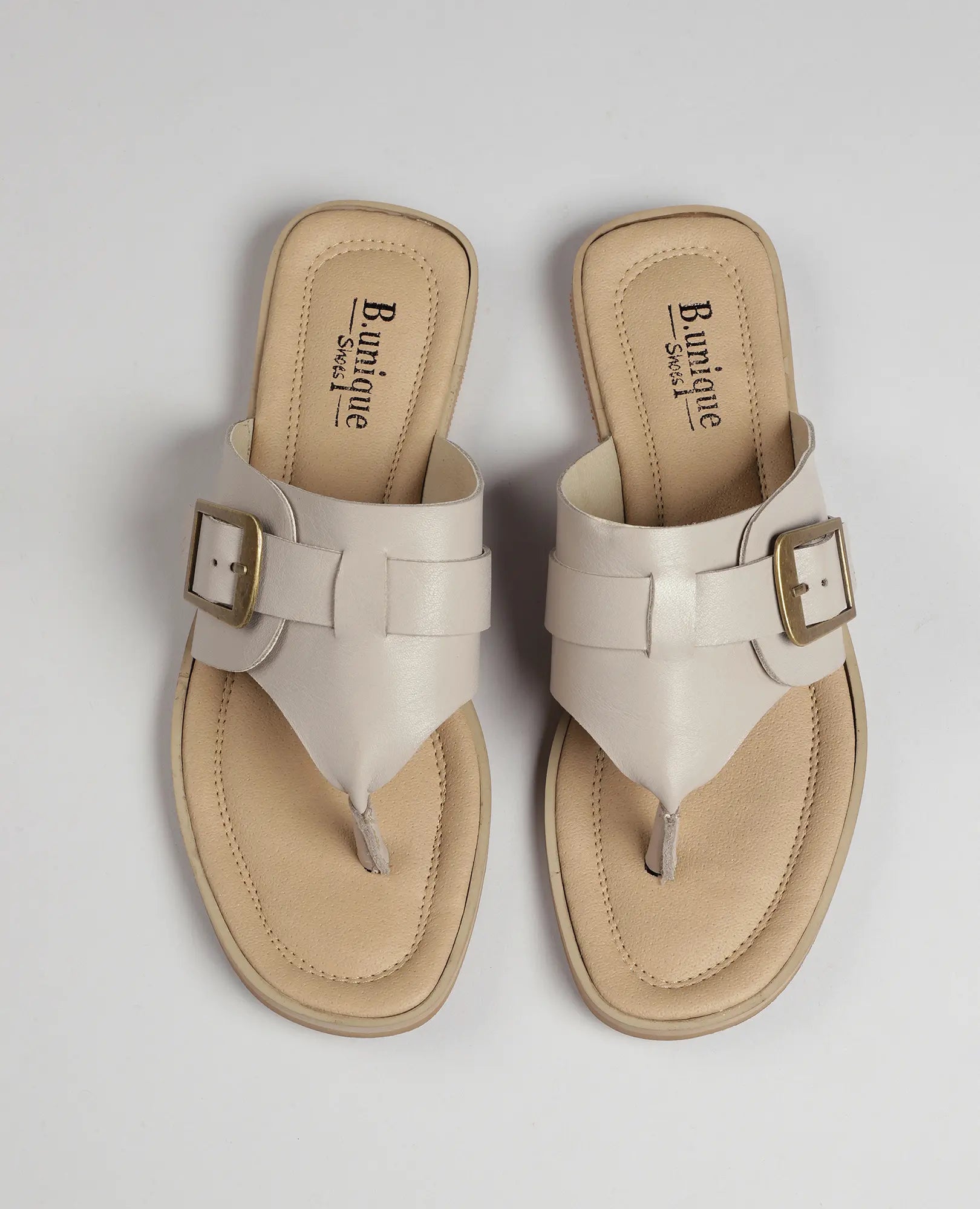 כפכפי אצבע עם אבזם לורל לנשים מבית B.unique, מעור איכותי בגוון בז' ורצועות זהב, מוצגים על רקע לבן.