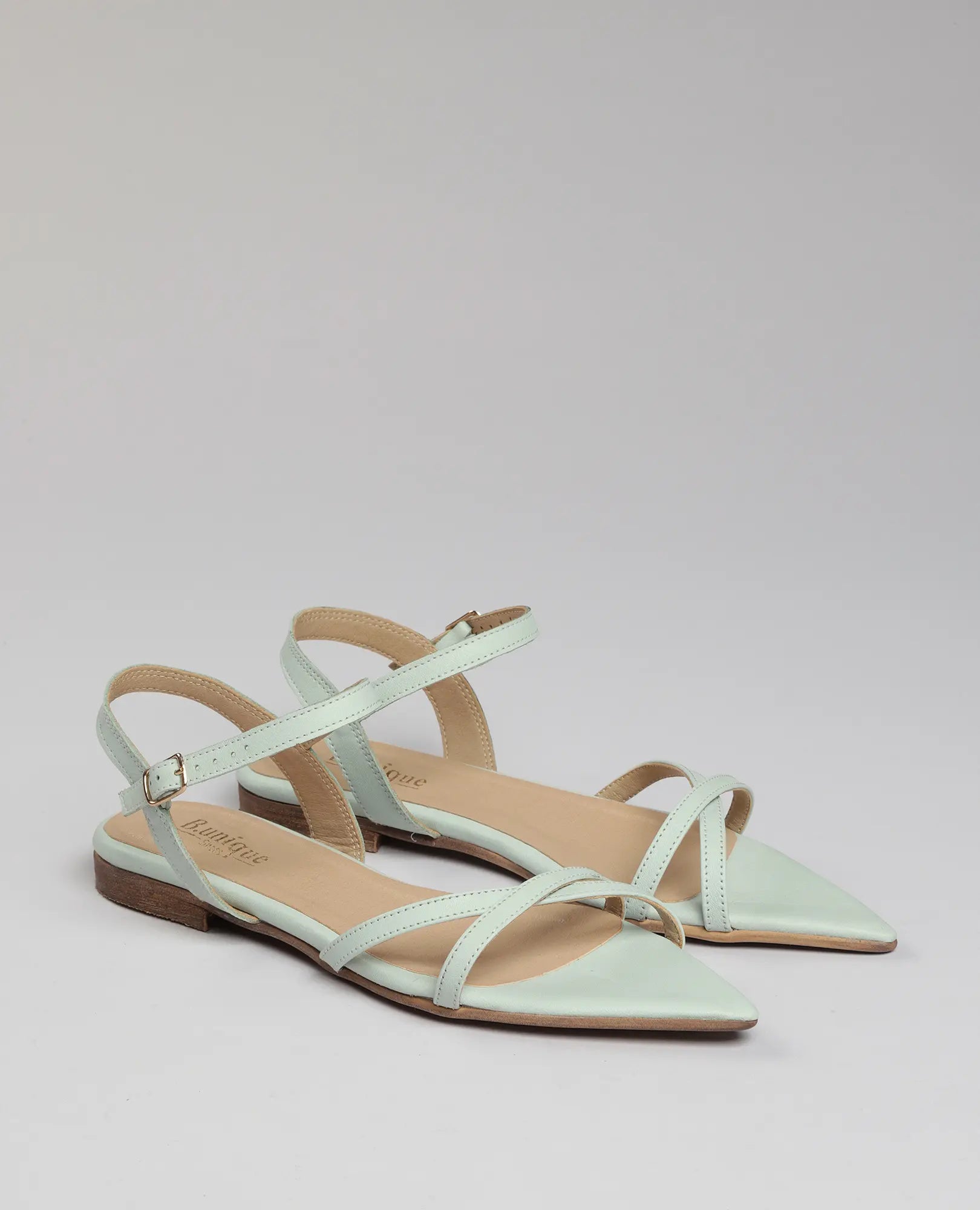 סנדלים שטוחות של B.unique – בלן בצבע ירוק בהיר עם רצועות דקות וסוליה נוחה, מוצגות על רקע חלק.