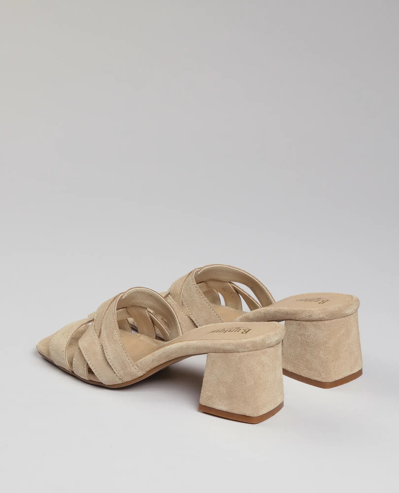 כפכפי עקב-מרגי של B.unique מעור זמש בז', עם עקב רחב ורצועות מוצלבות, על רקע לבן.