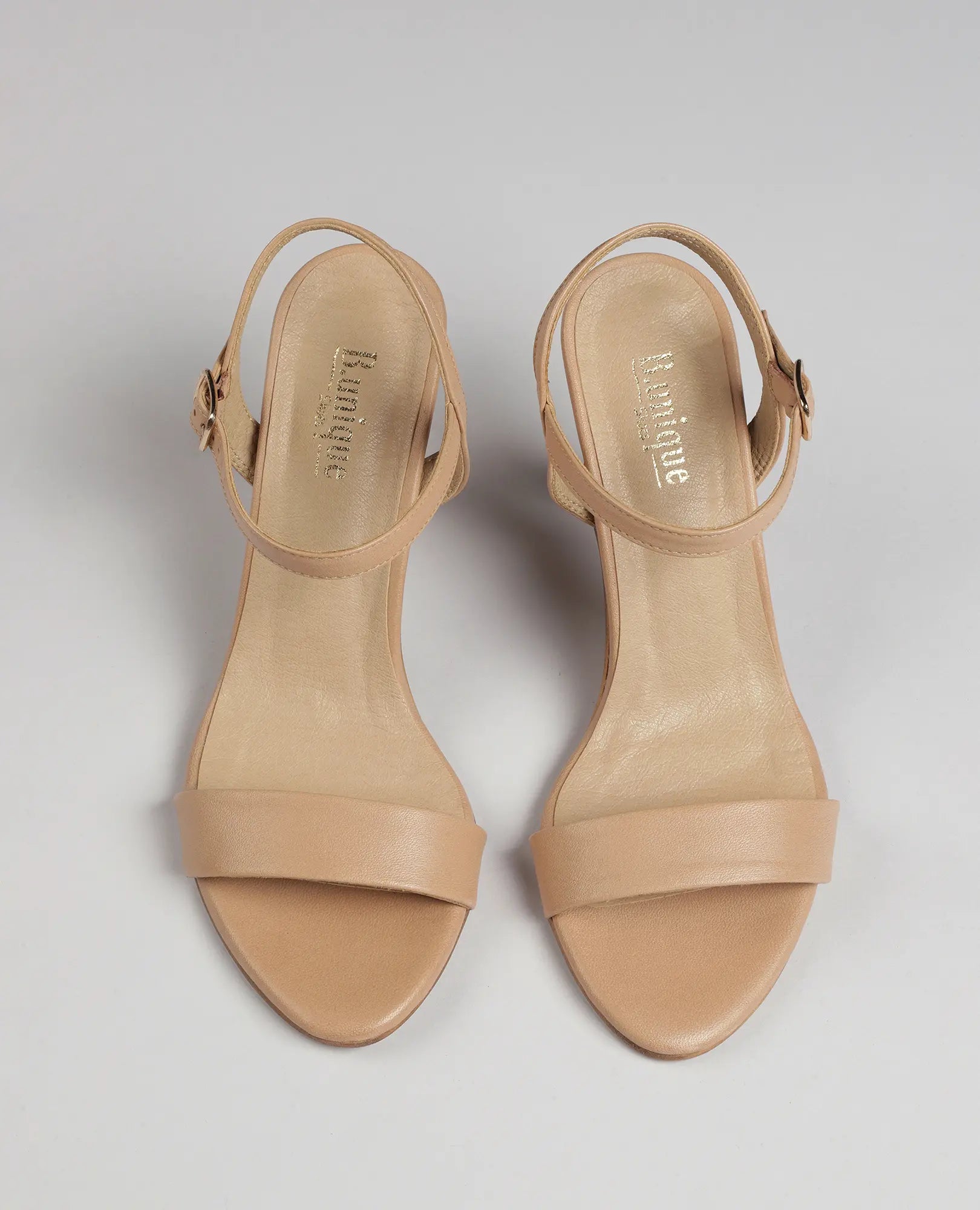 זוג סנדלי עקב גבוהים בצבע בז' מדגם "גלן" של B.unique, עם אצבעות חשופות, רצועות בקרסול ועקבים גבוהים, במבט מלמעלה.