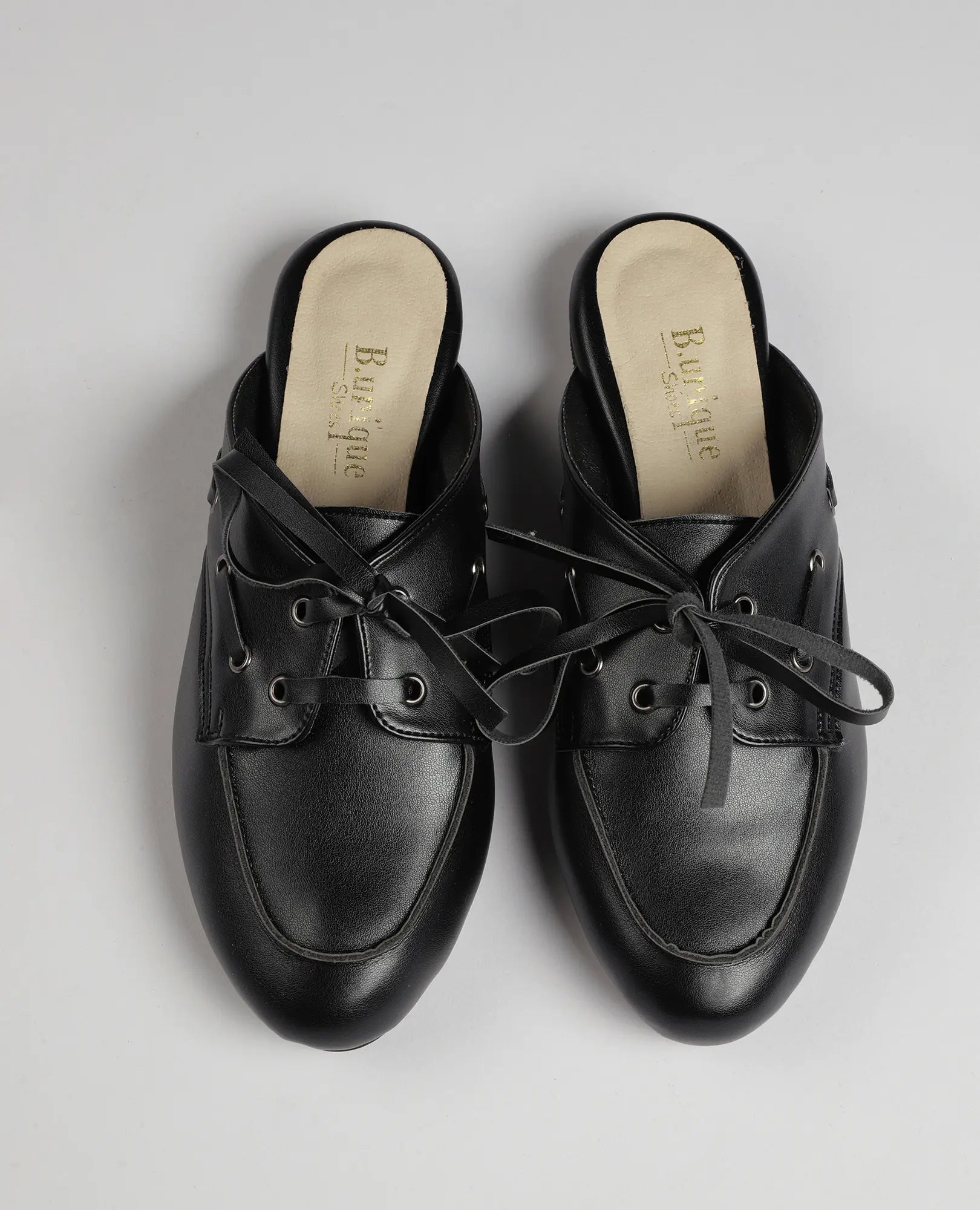 כפכפי מוקסין-לירי דמוי עור שחורות עם שרוכים מבית B-Unique VEGAN, על רקע אפור בהיר.