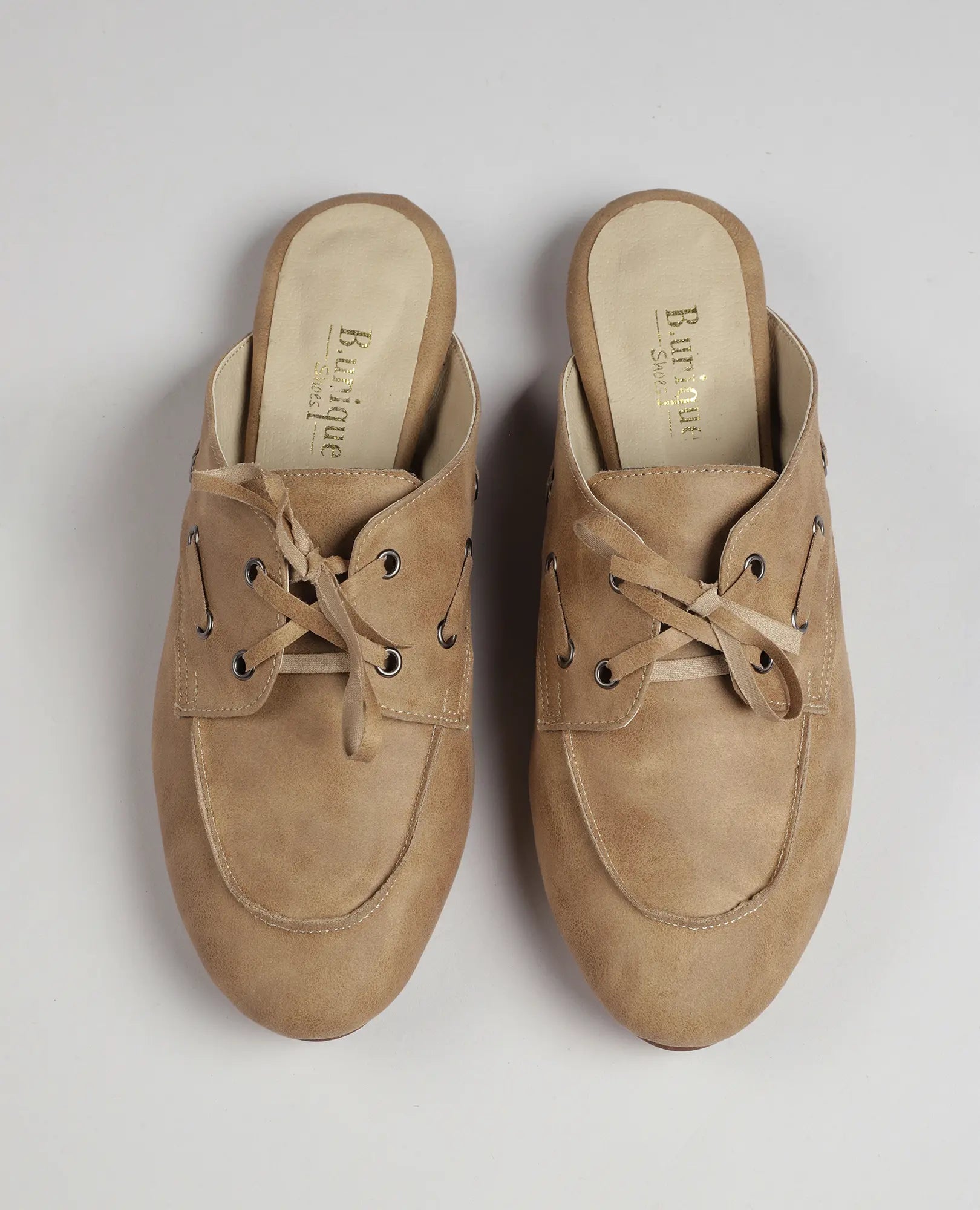 כפכפי מוקסין-לירי בצבע טאן של B-Unique VEGAN, דמוי עור עם שרוכים, בעיצוב אופנתי על רקע ניטרלי.