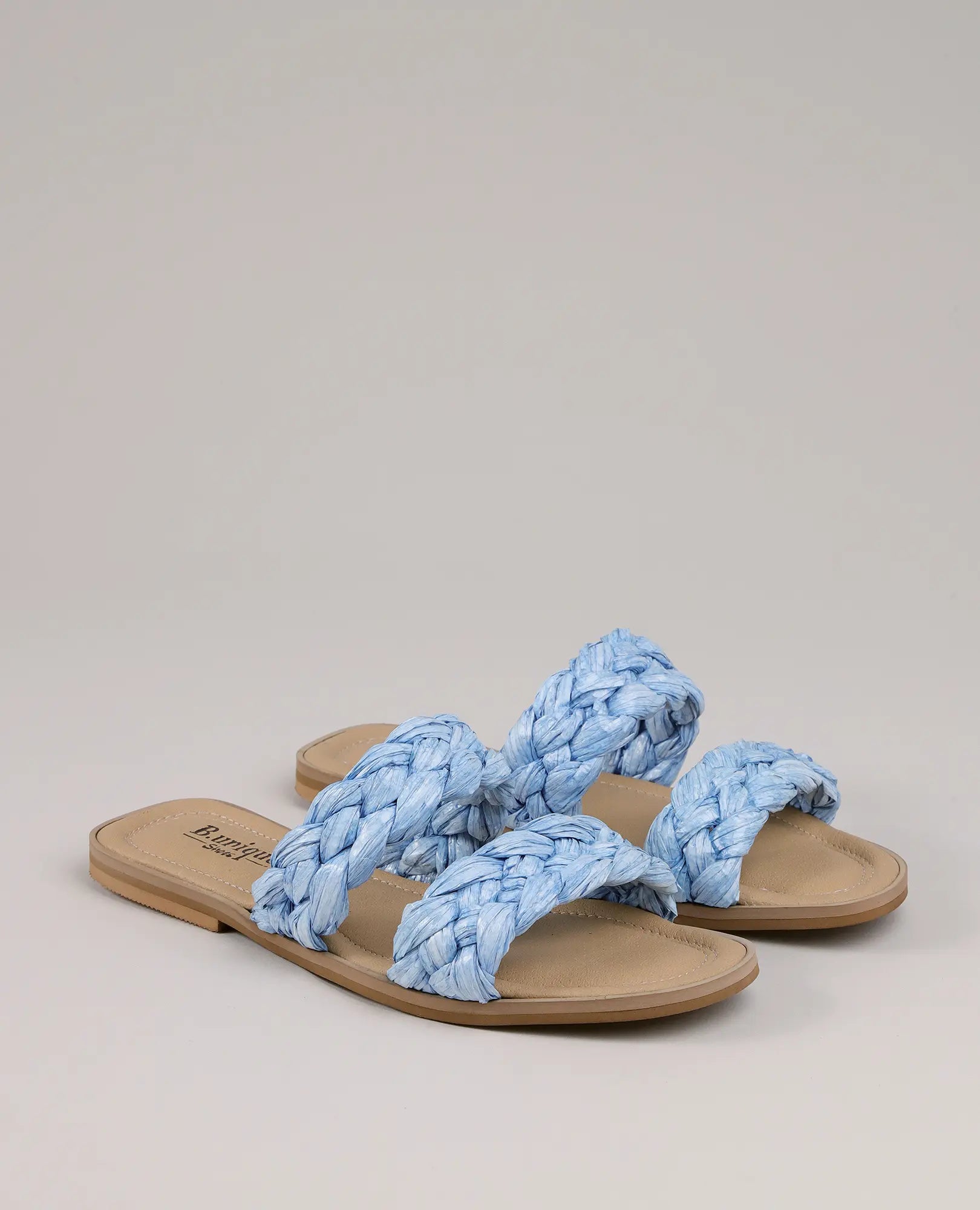 כפכפי רפיה עם צמות – אלינור מבית B-Unique VEGAN, עם סוליות בצבע טאן ושתי רצועות קלועות כחולות בכל כפכף.